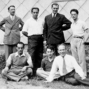 Black and white historical photo of eight men in front of a building, including Henri Cartan, André Weil and Szolem Mandelbrojt.
