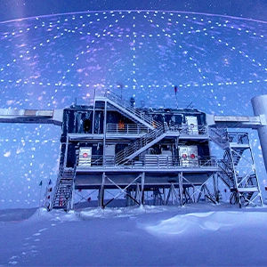 A photo illustration showing a research station in Antarctica with a map plotting neutrinos’ arrival directions imprinted on the sky.