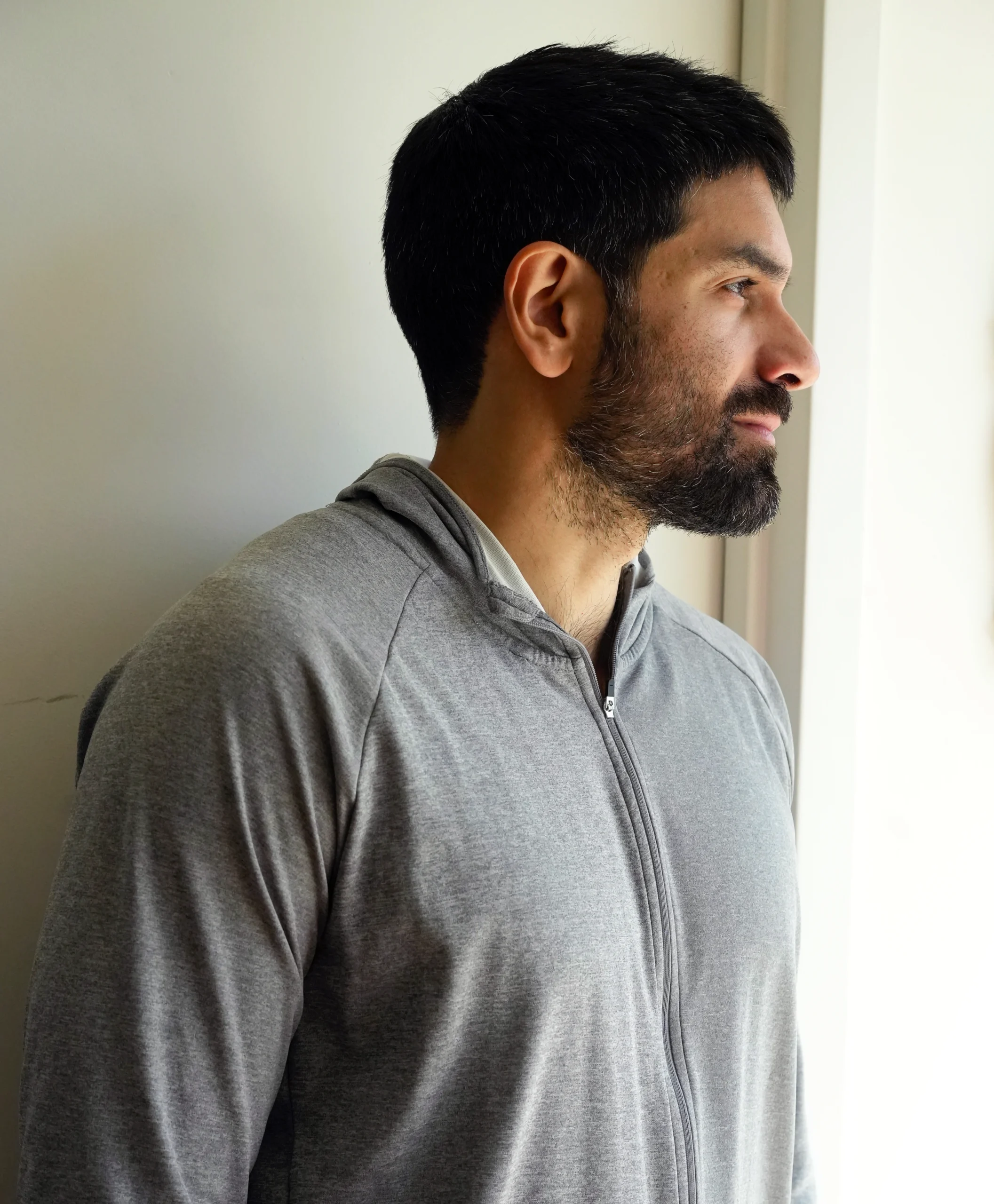 Man in a gray sweatshirt standing in profile.
