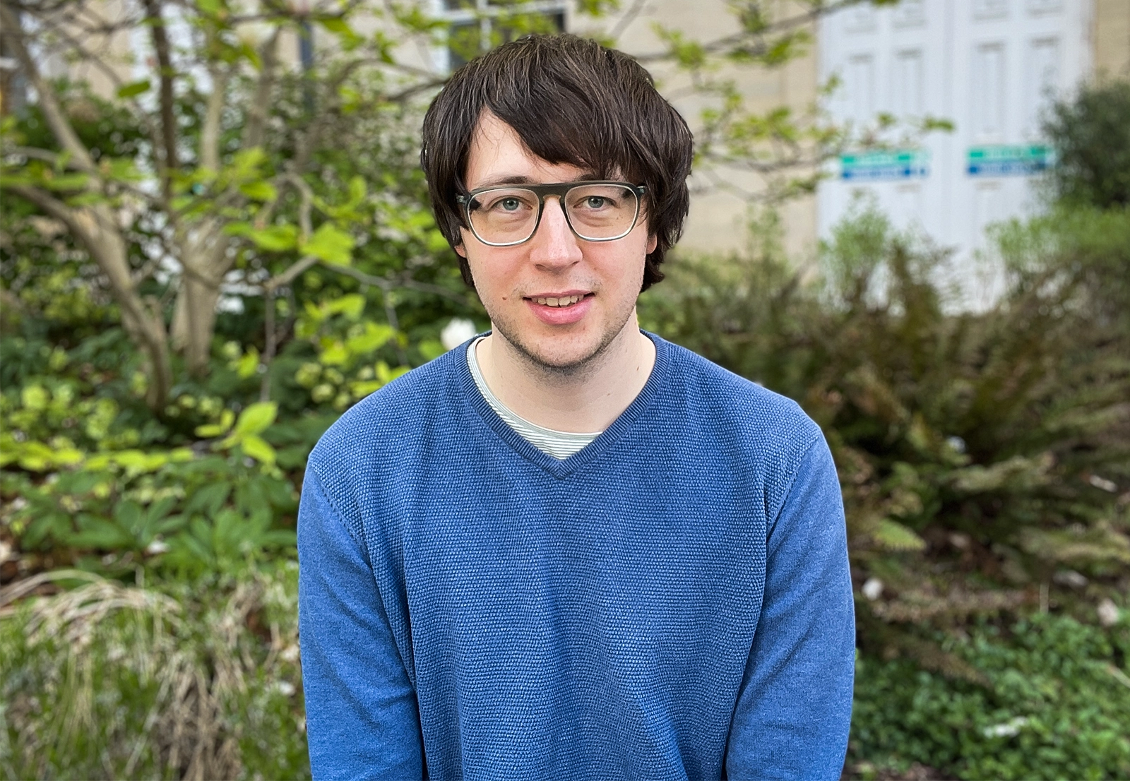Man with dark hair and glasses, smiling.