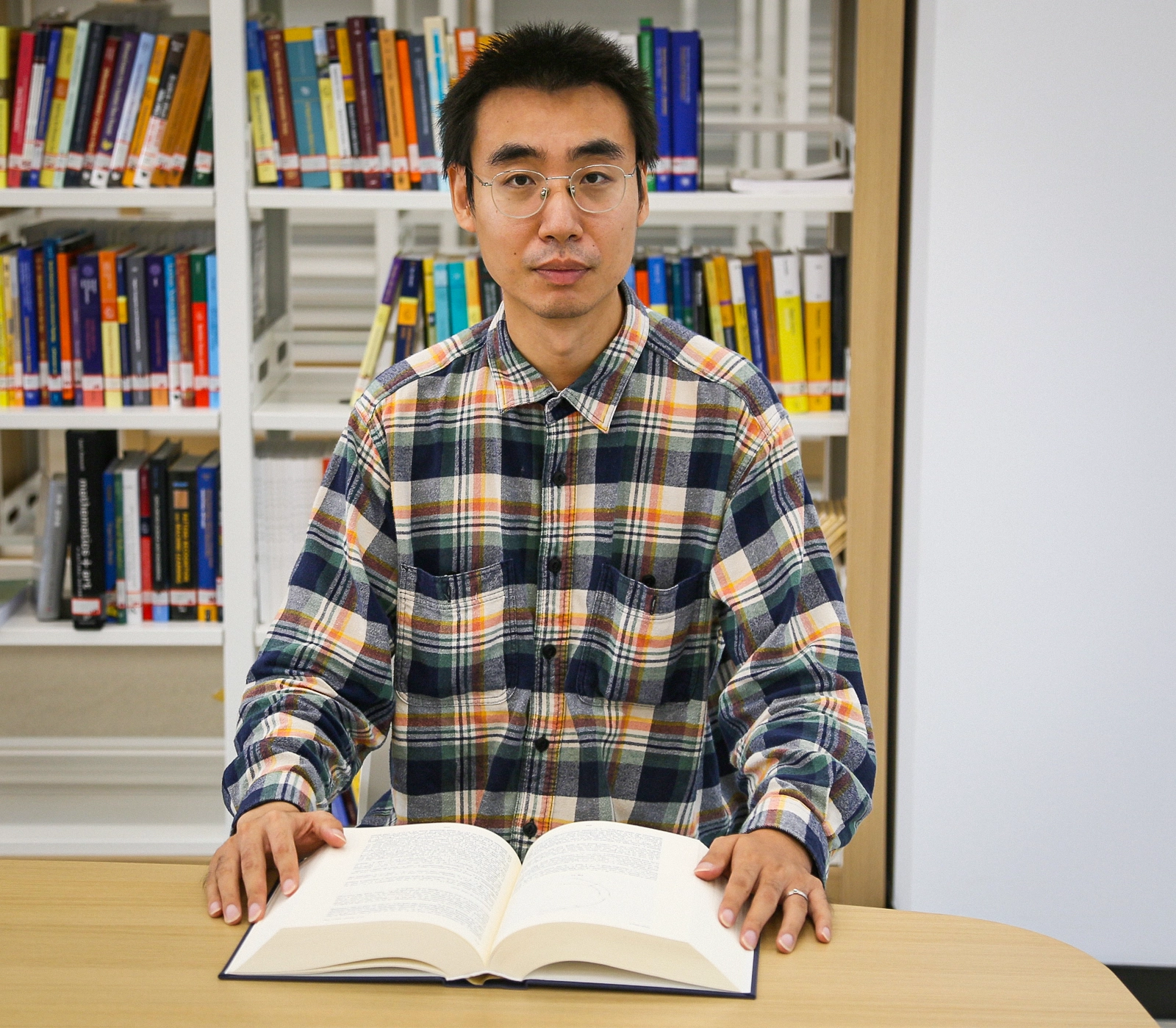 Man sitting at desk with a book open in front of him.