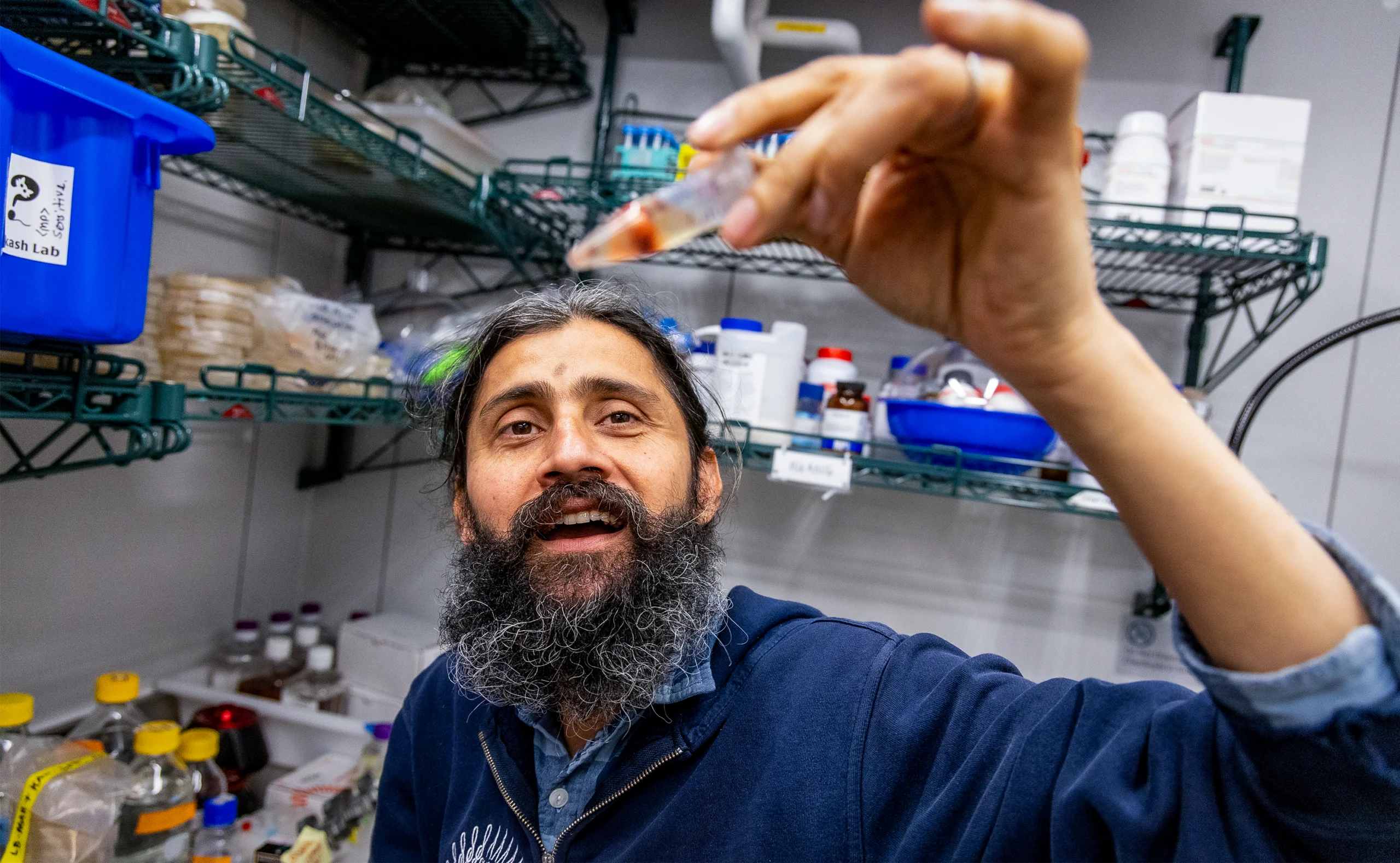 Manu Prakash holds up a small tube with a red blob inside.