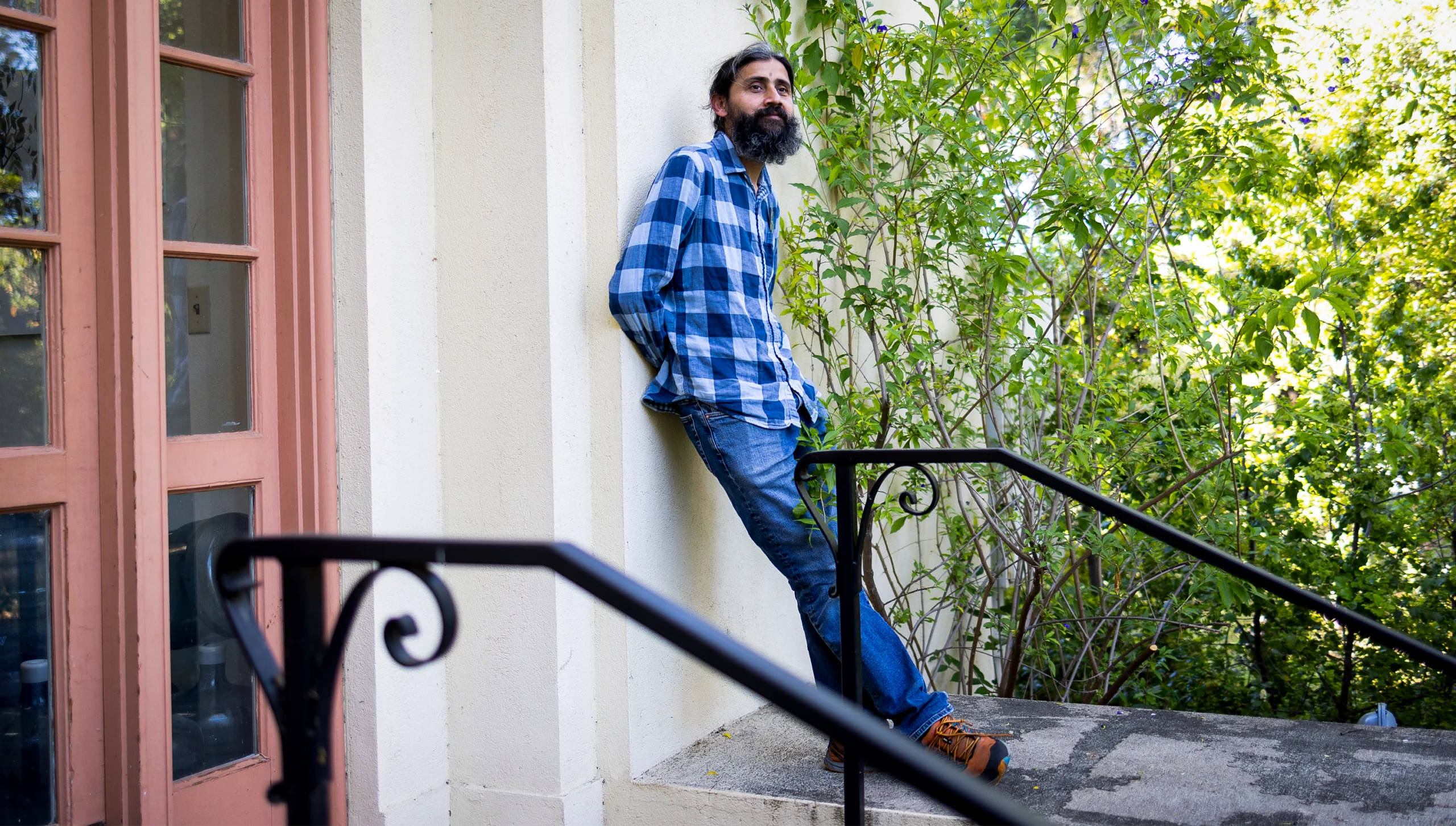 Manu Prakash leans against a building on Stanford University’s campus.