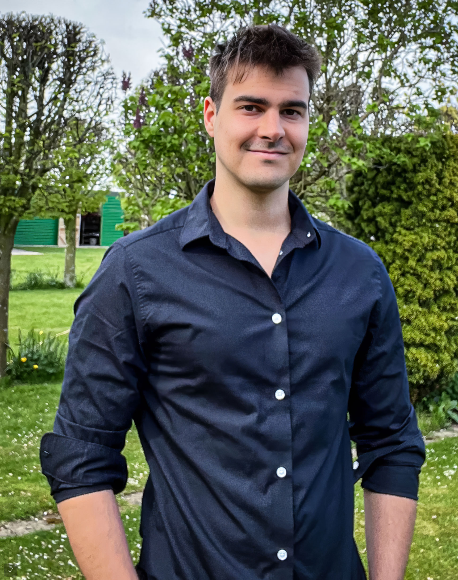 : Martín Costa in a black shirt stands outside in front of green trees