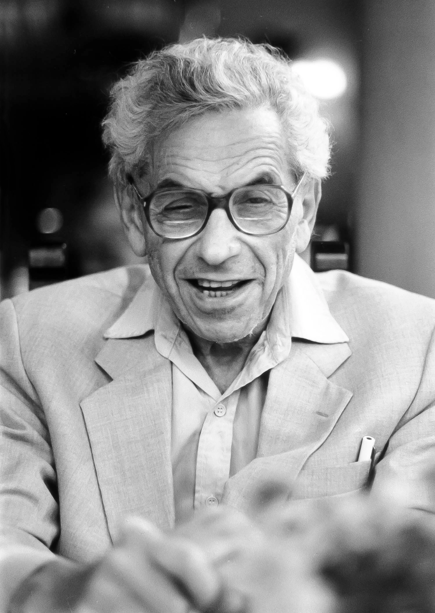 Black-and-white photo of a man in glasses, making a funny face.