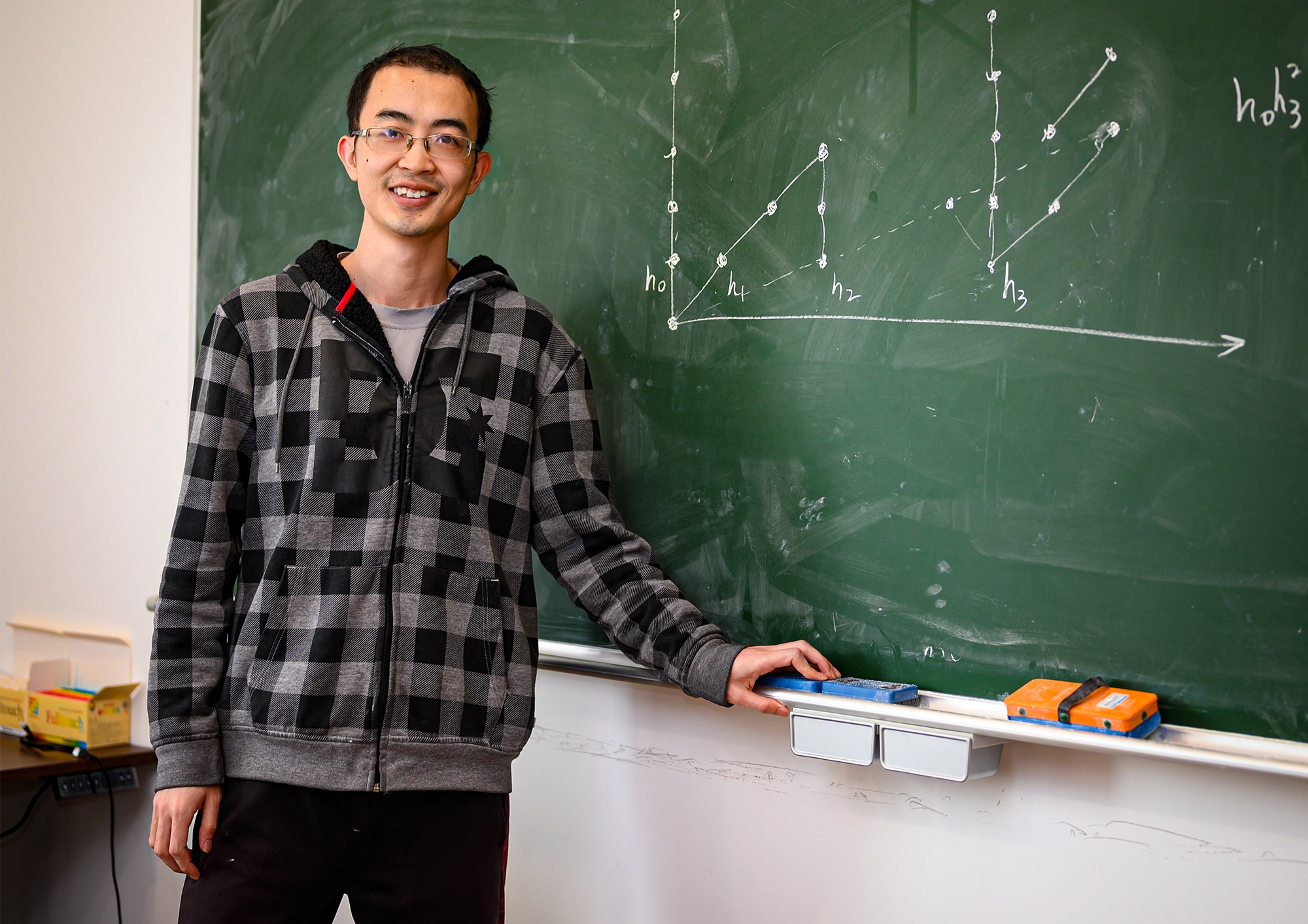 Man at a blackboard filled with drawings of dots and lines.