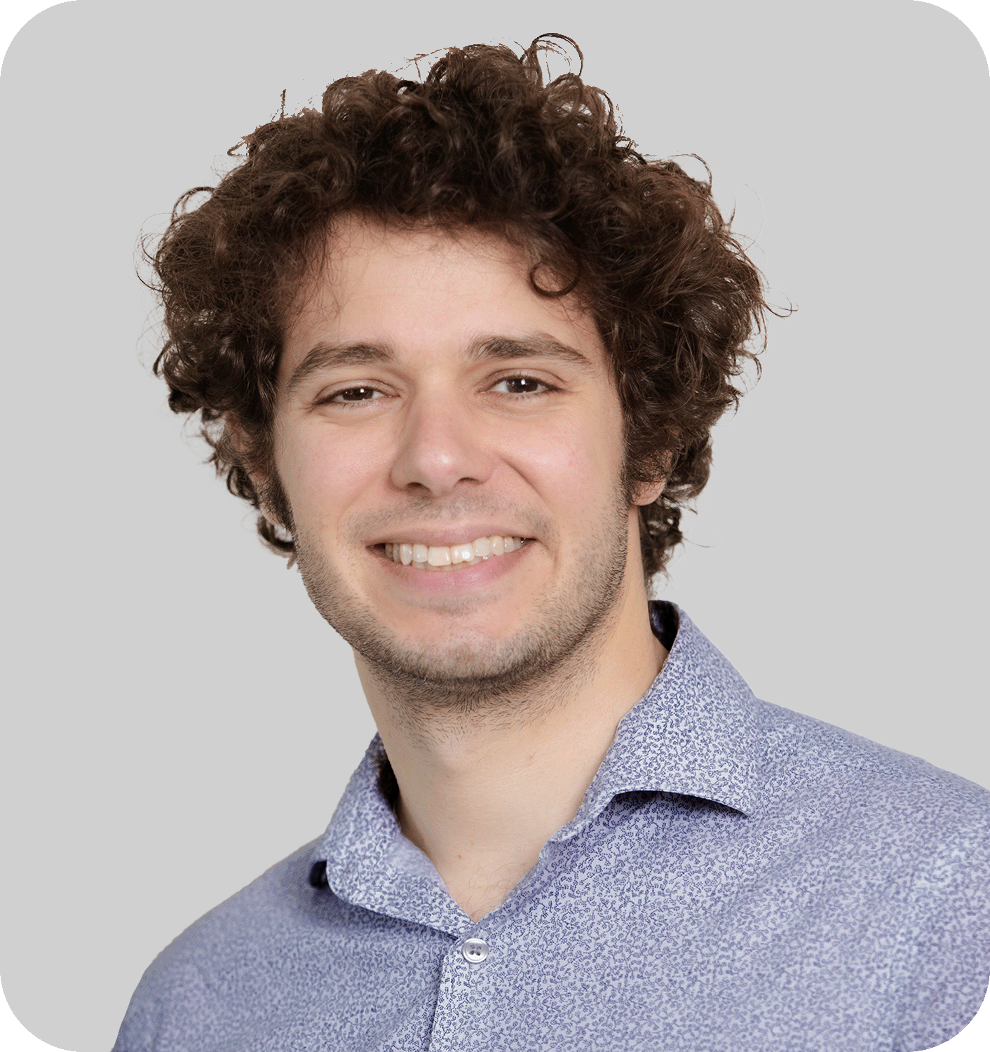 A smiling man with curly brown hair