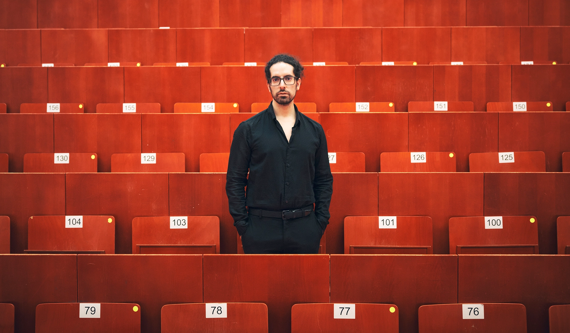Man dressed in black standing in an auditorium.