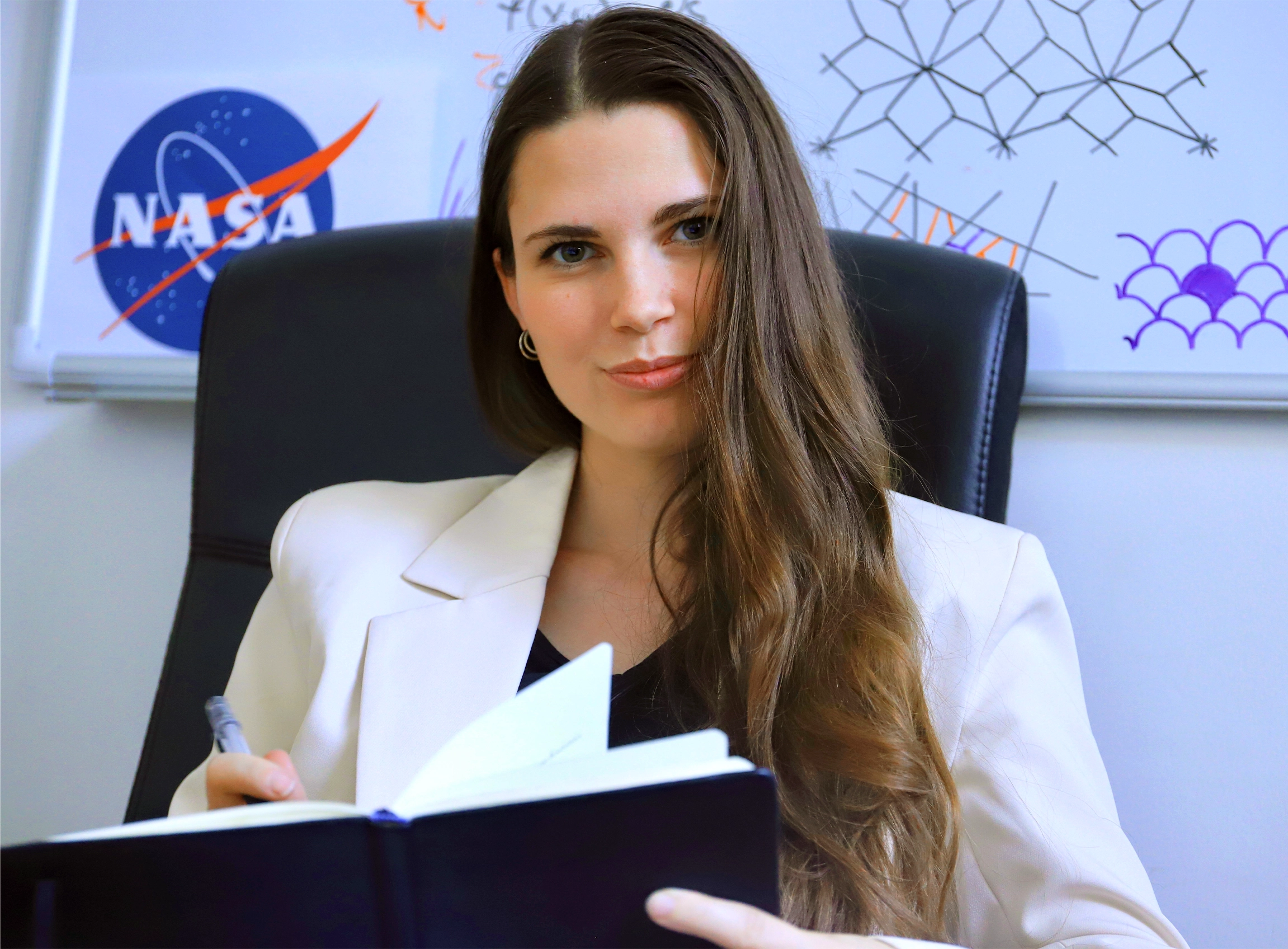 woman with long dark hair in front of a whiteboard