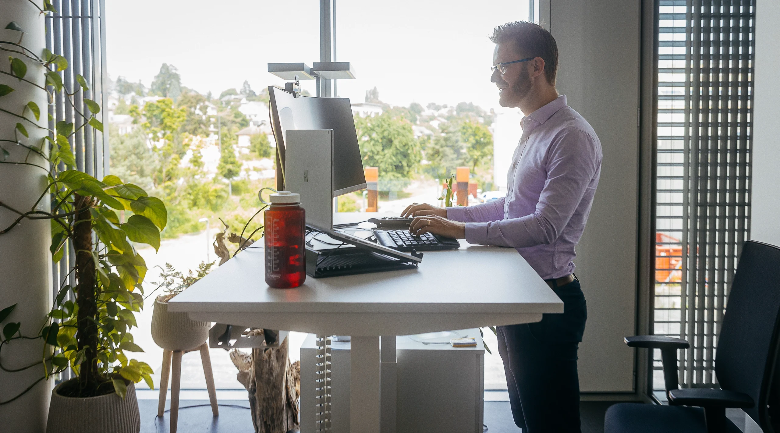 Martin Schrimpf stands at a white desk working on a computer in front of a window