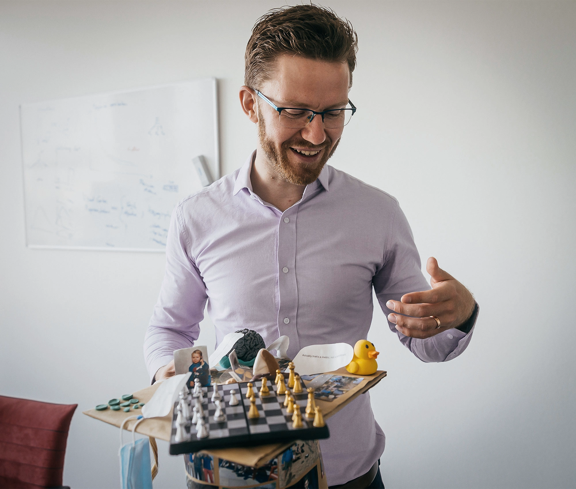 Martin Schrimpf in a purple shirt holds a chess set, rubber duckie and more