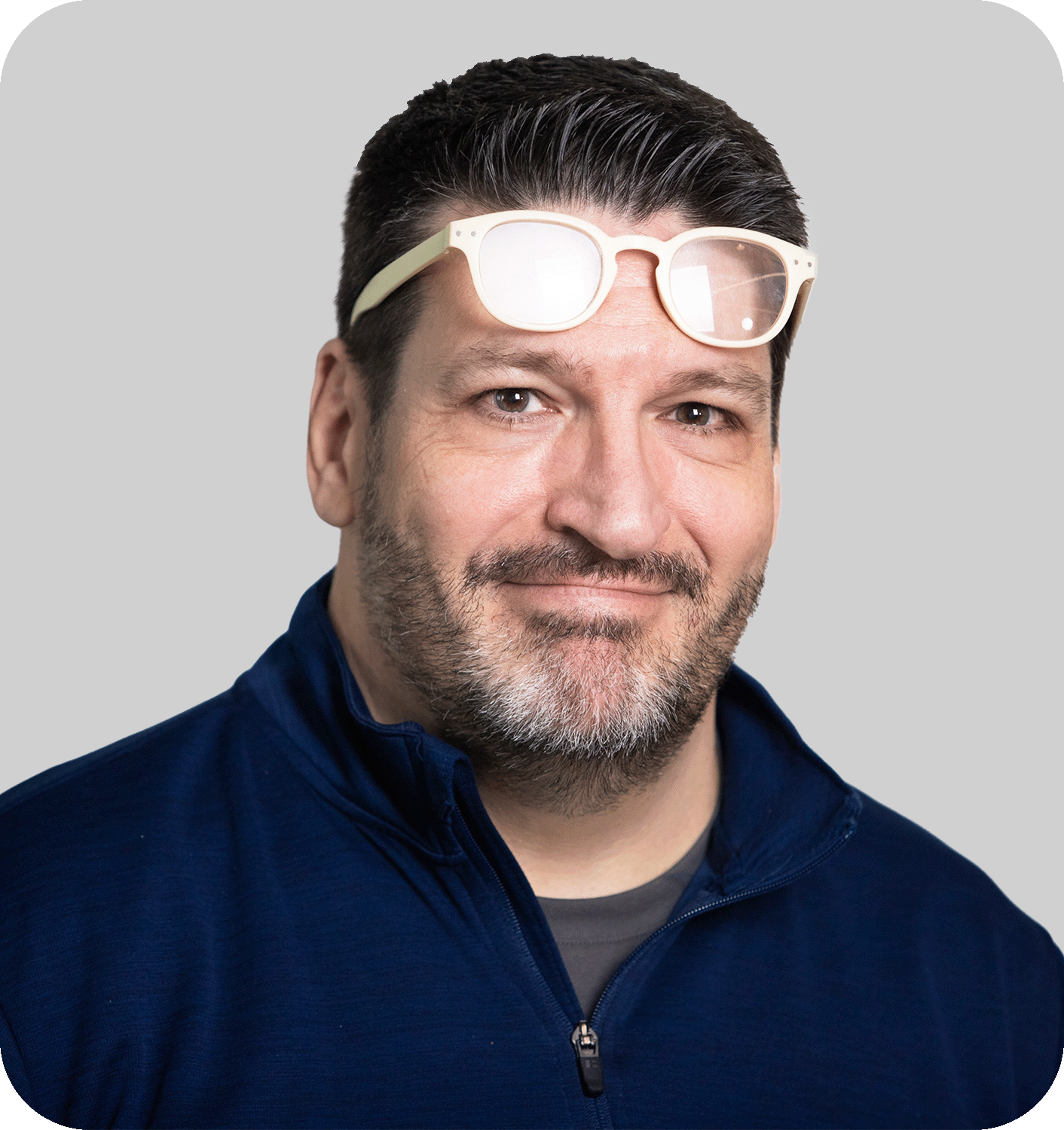 A smiling man with black hair and white glasses on his head