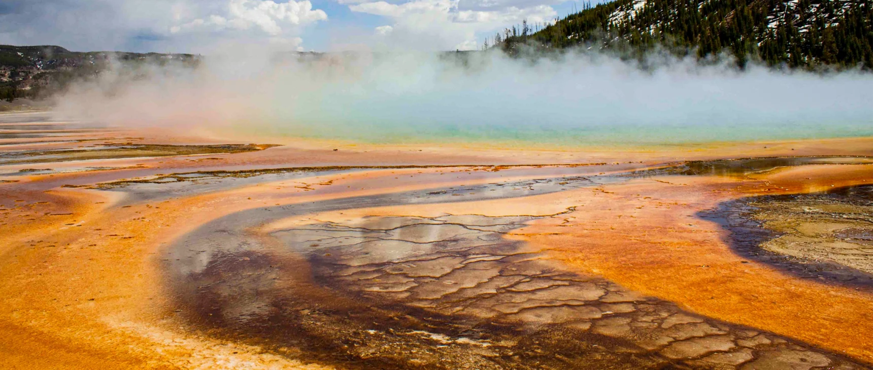 Steam billows off a colorful hot spring.