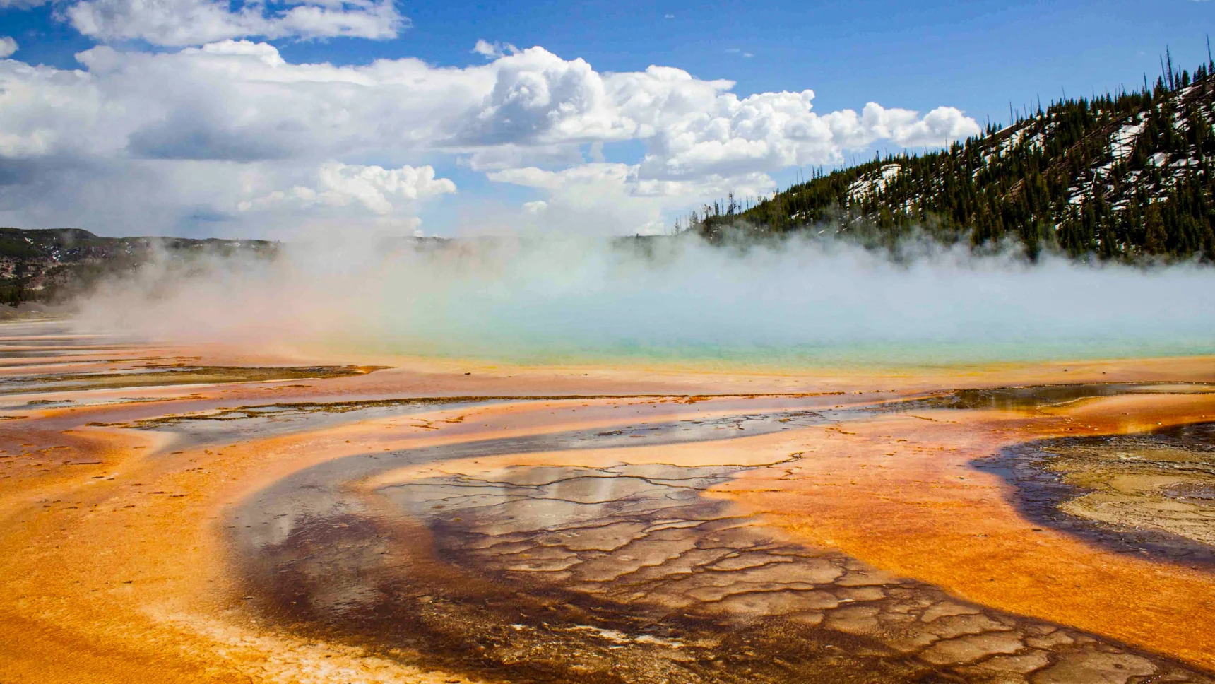 Steam billows off a colorful hot spring.