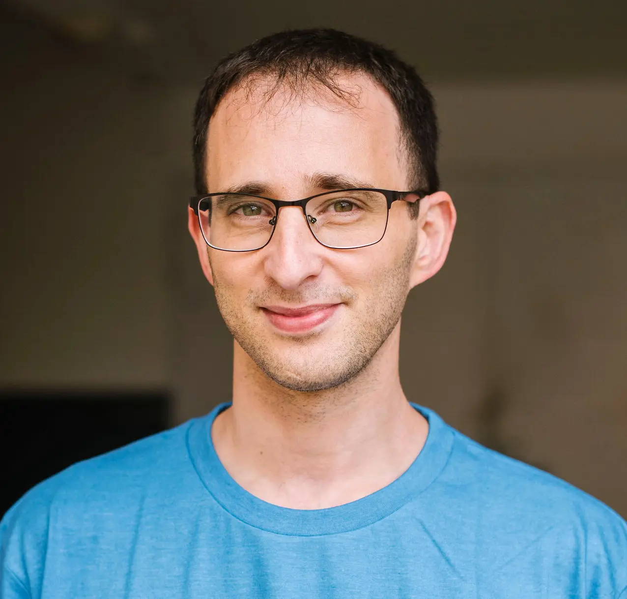 Eylon Yogev, a computer scientist, wearing a mid blue T-shirt and smiling at the camera.
