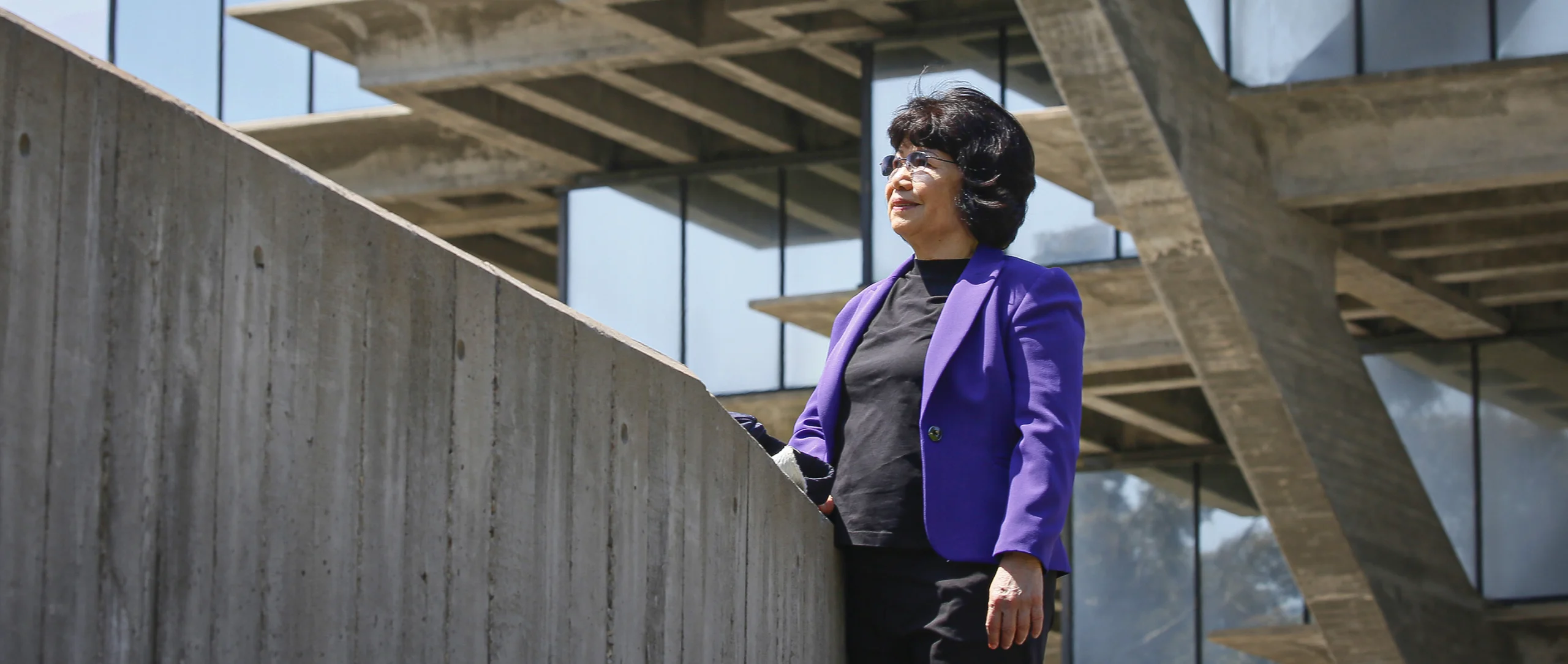 Woman in a purple suit standing outside.