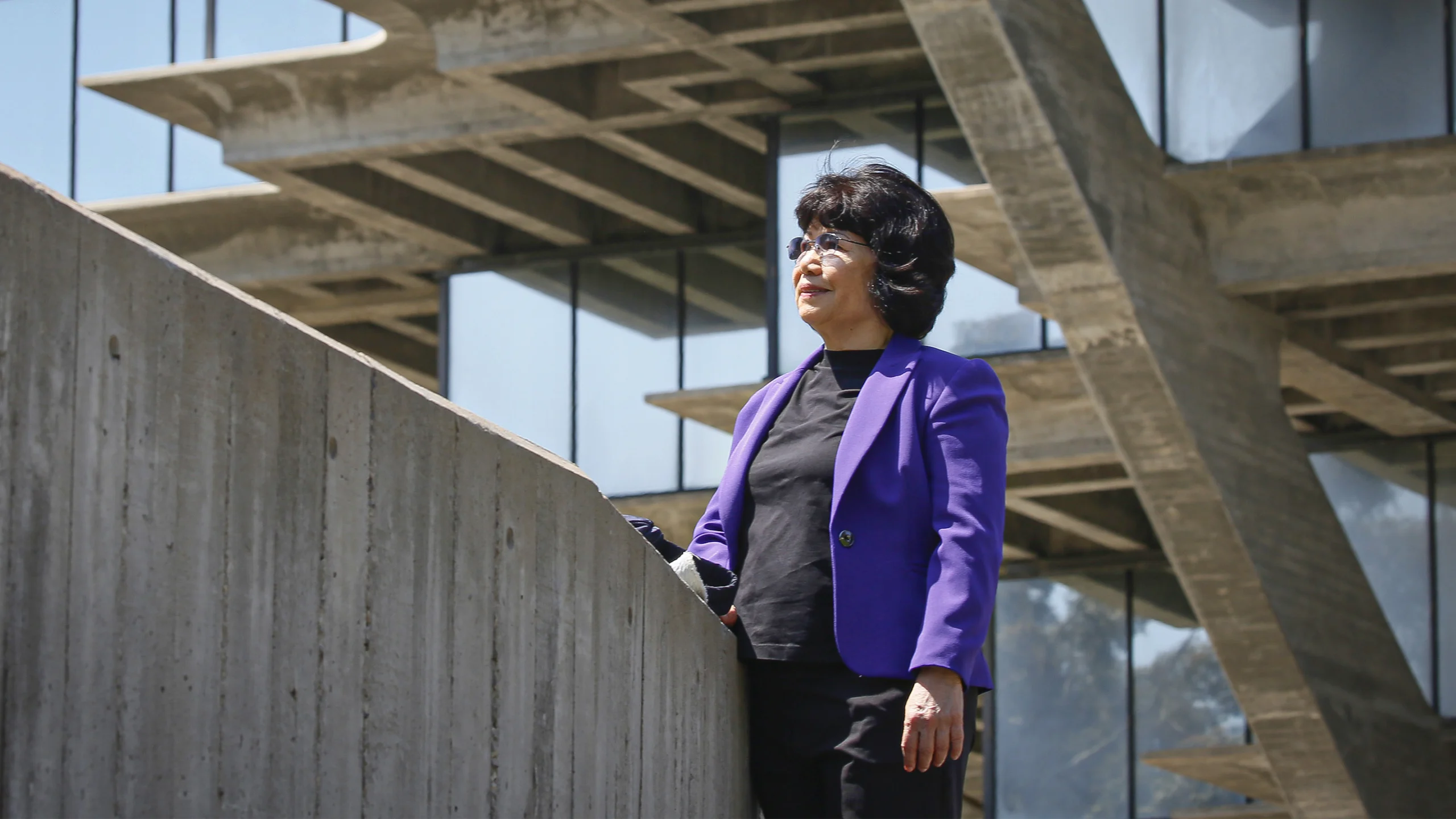 Woman in a purple suit standing outside.