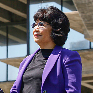 Woman in a purple suit standing outside.