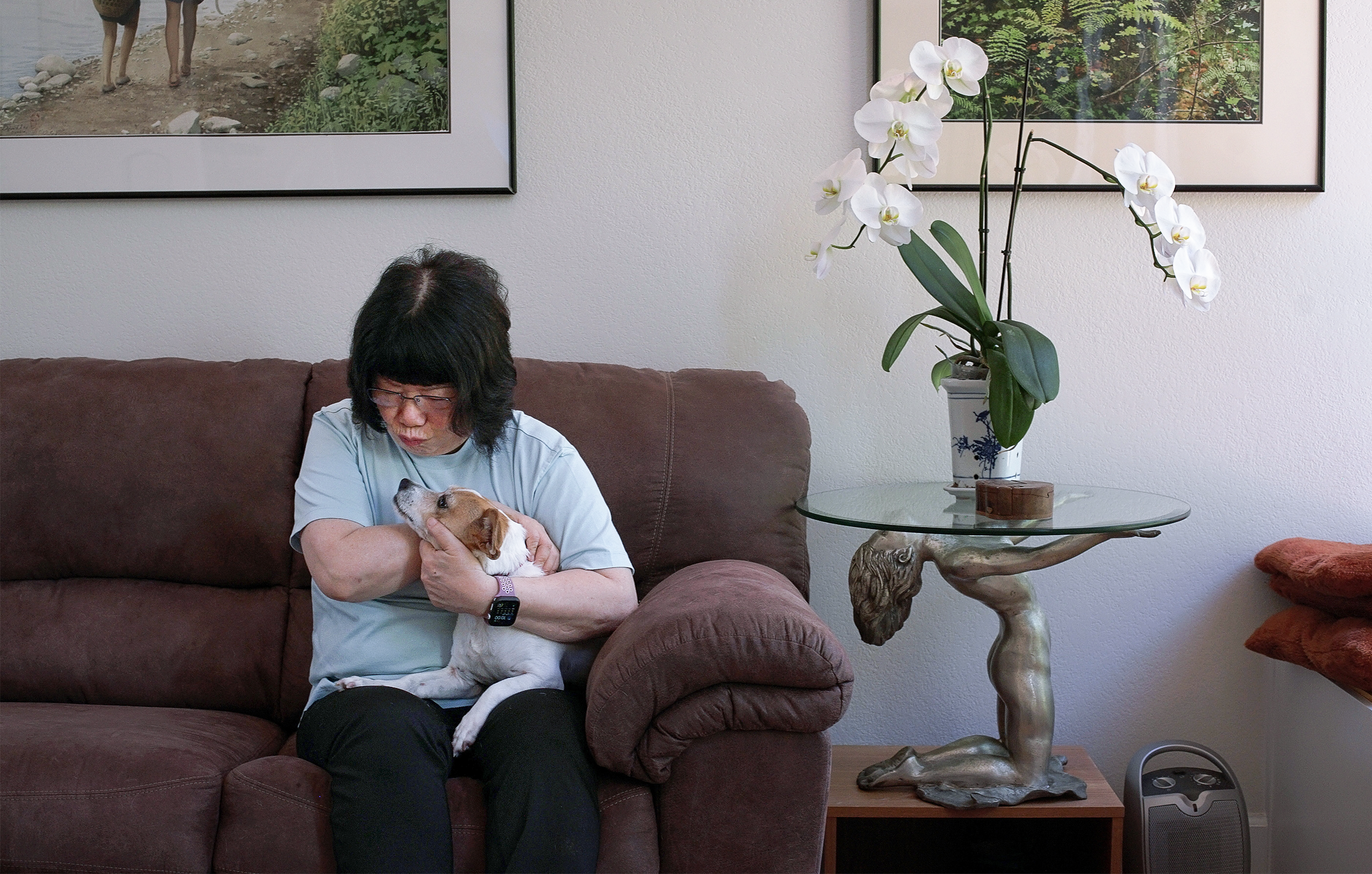 A woman holds her dog while sitting on a couch.