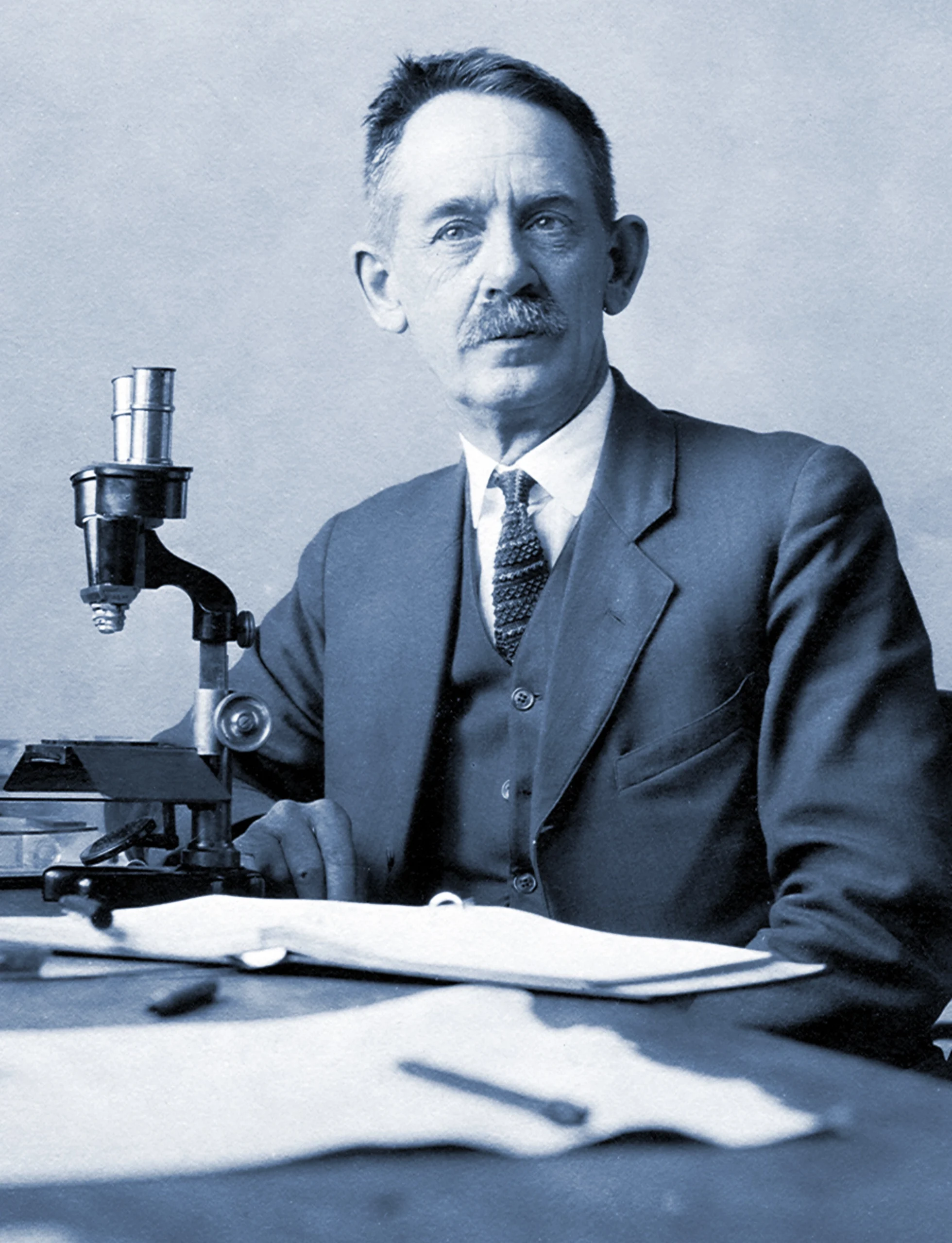 The zoologist Herbert Spencer Jennings sits in front of a microscope.