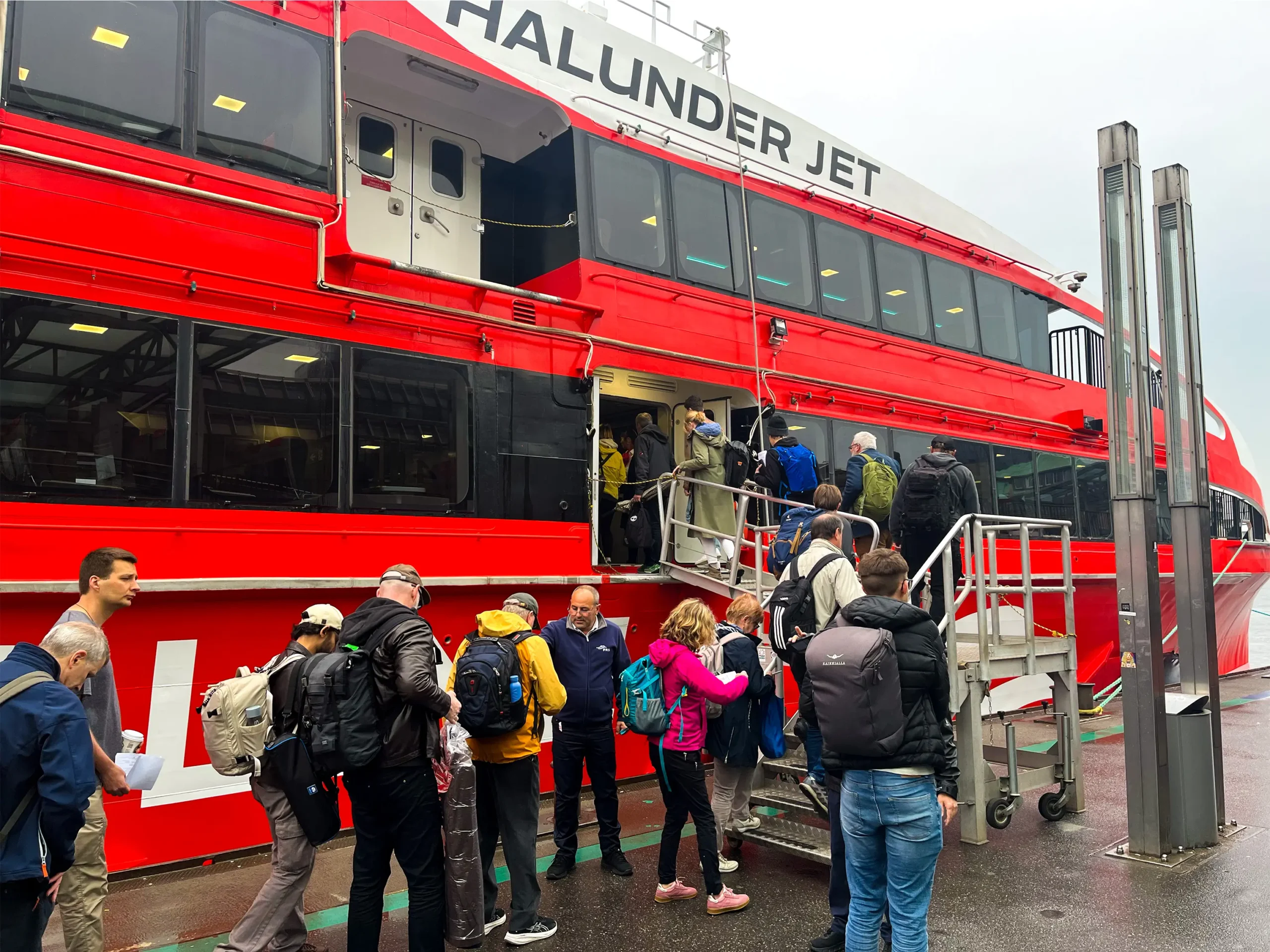 Physicists line up to board a large red-and-white boat, the Halunder Jet.
