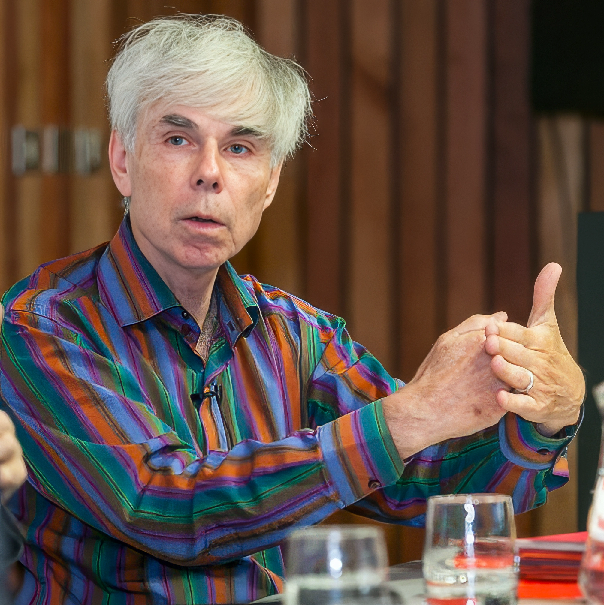 White-haired man wearing a colorful shirt.