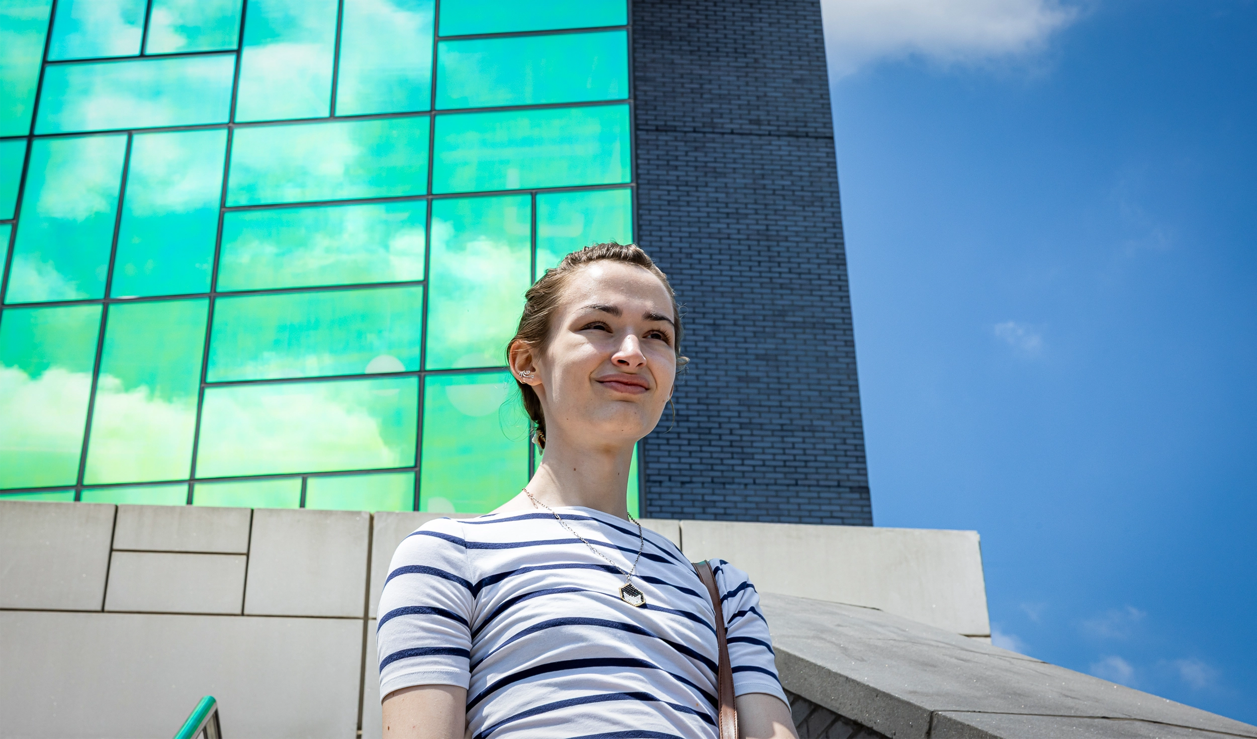 Woman standing in front of a reflective building.