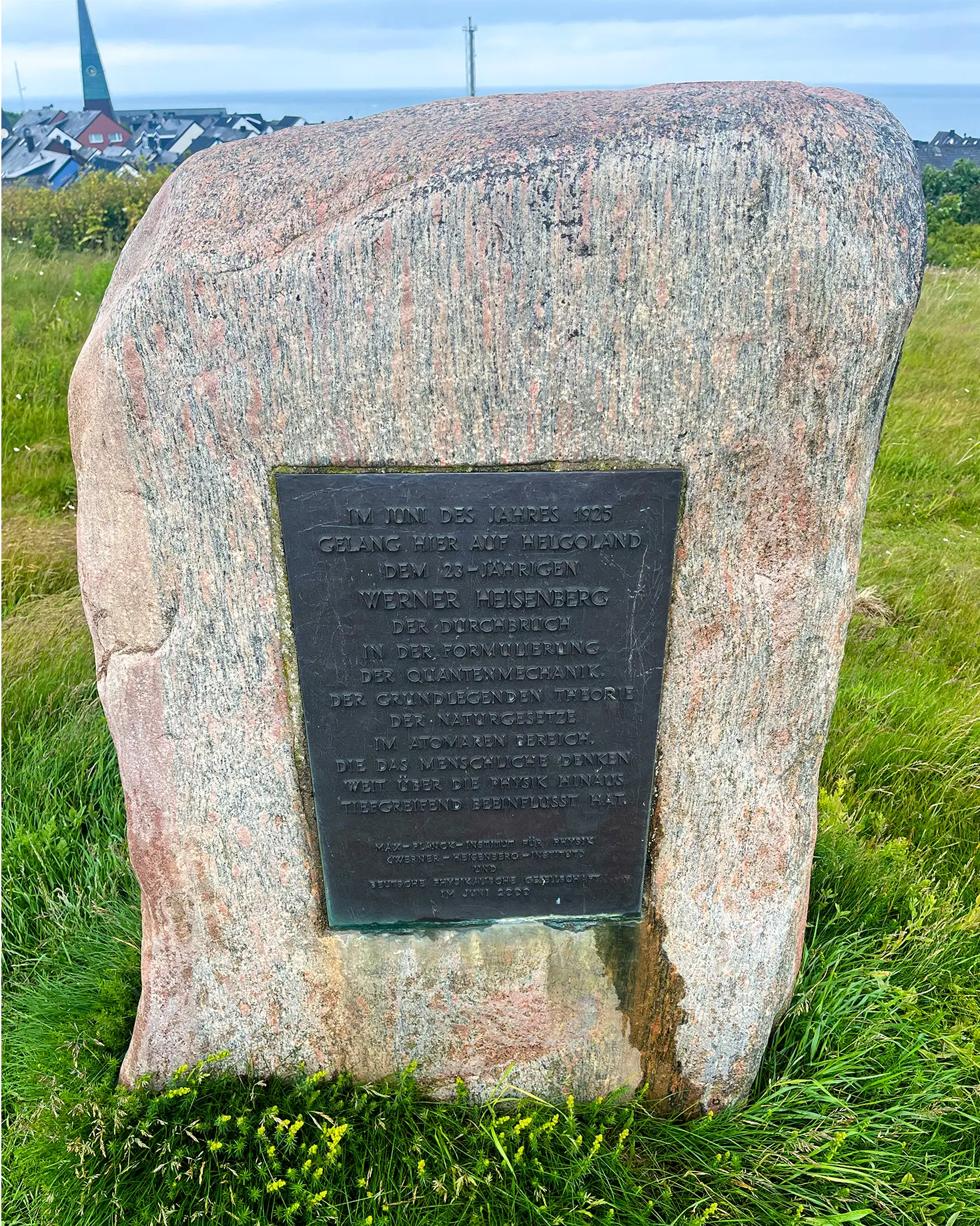 A stone features a metal plaque describing Heisenberg’s work in German.