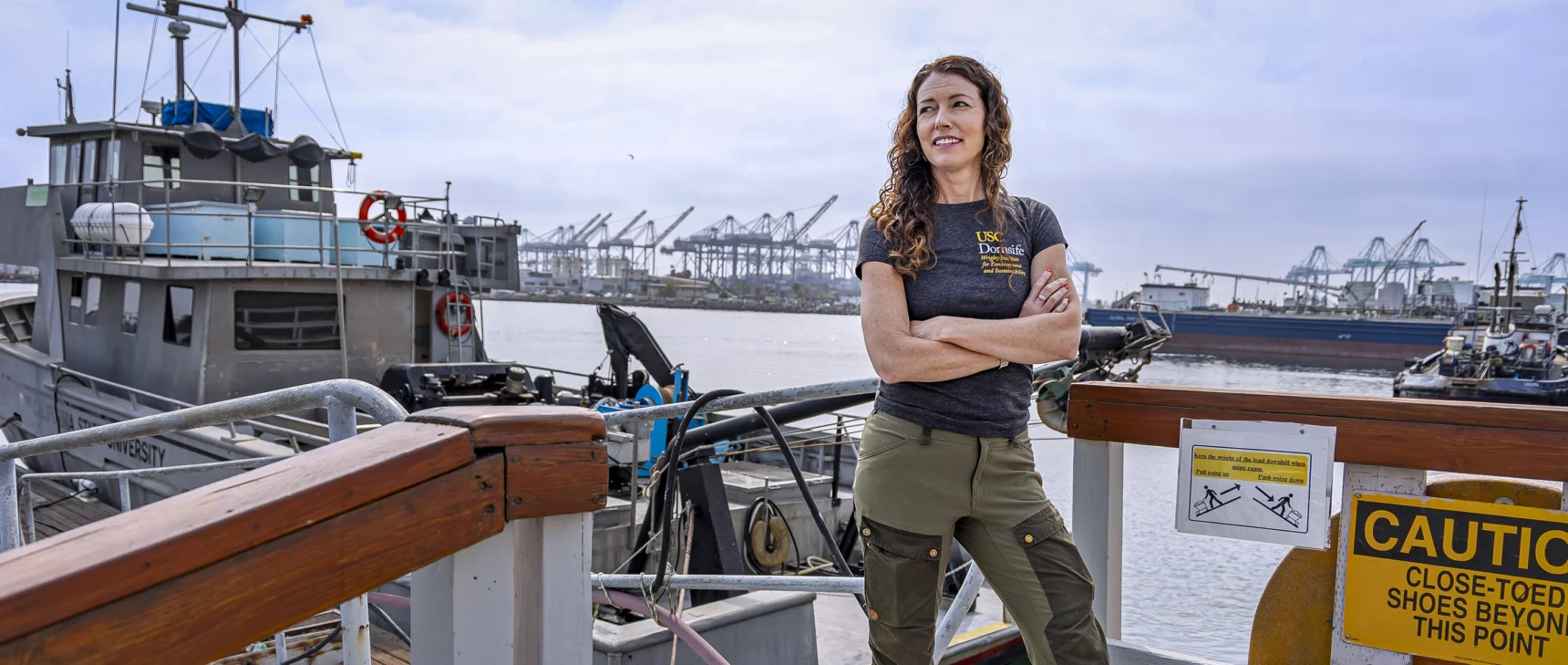 A woman standing next to a boat with her arms crossed