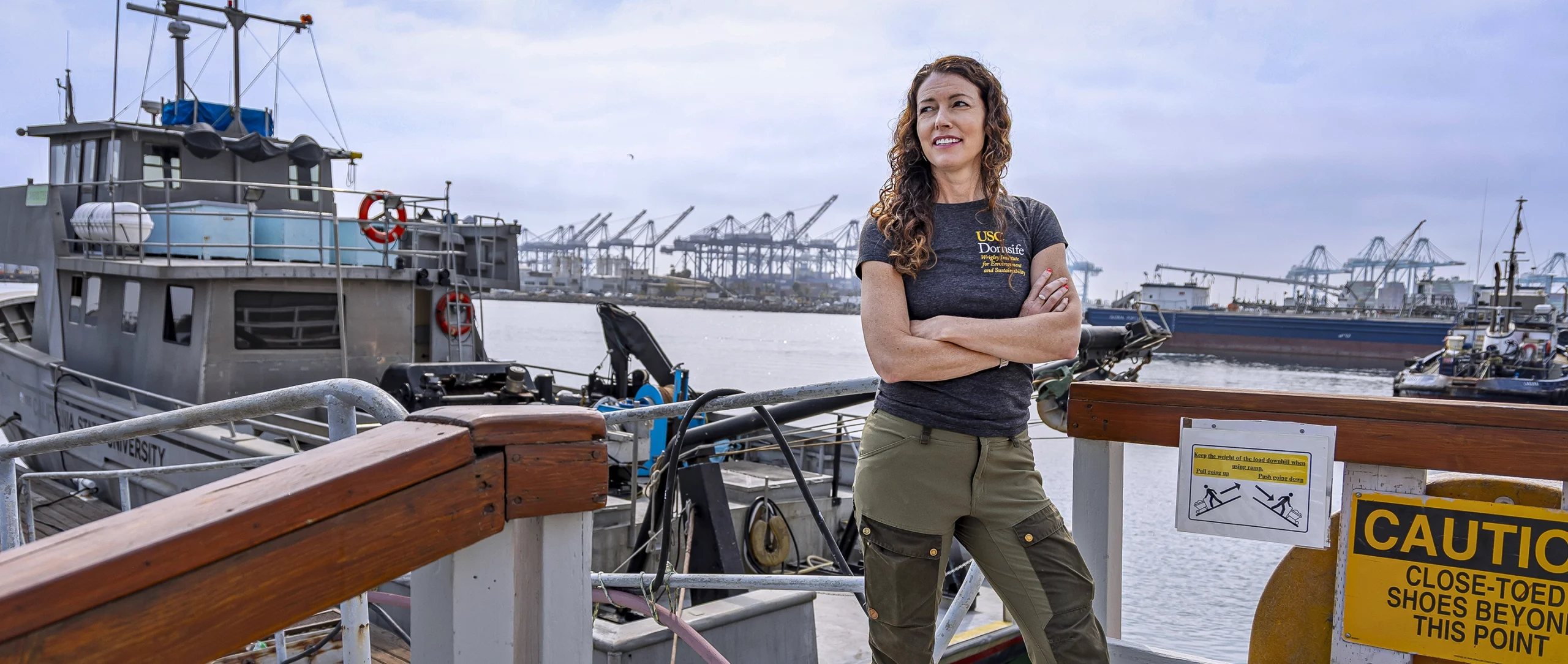 A woman standing next to a boat with her arms crossed