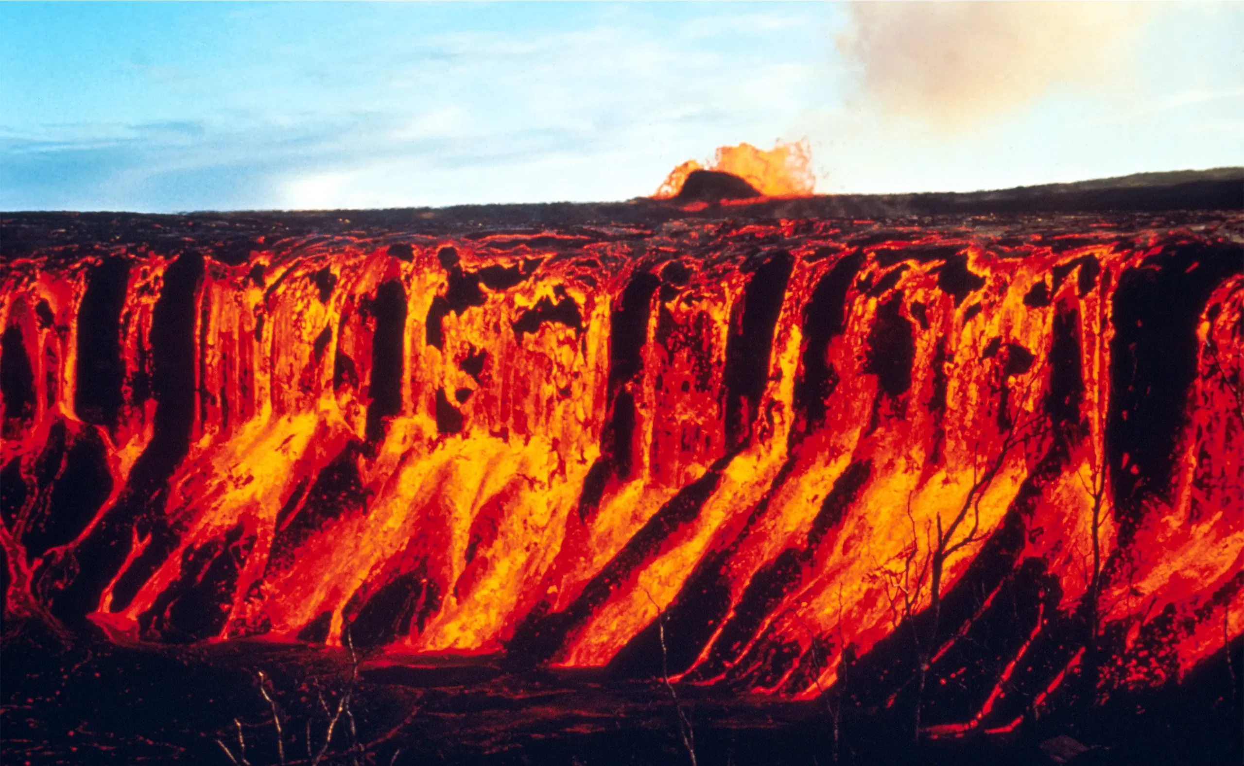 Red lava flowing down a cliff face.