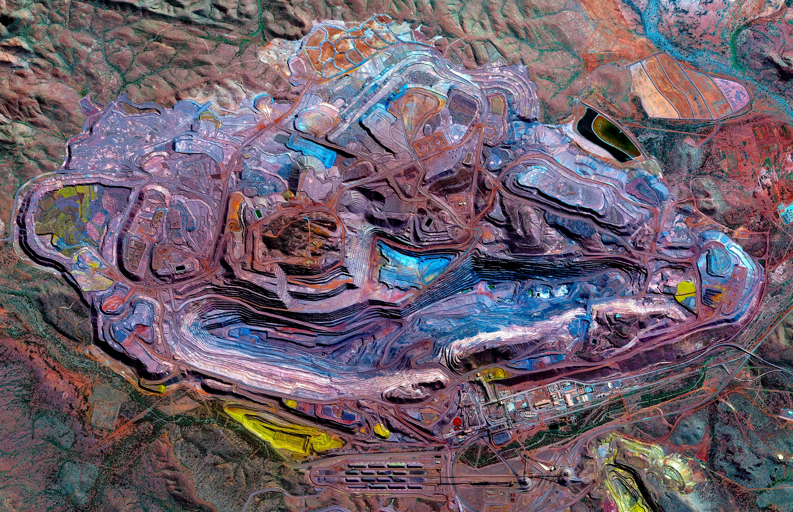 An overhead image shows a densely carved landmass in a variety of colors: purples, reds, blues.
