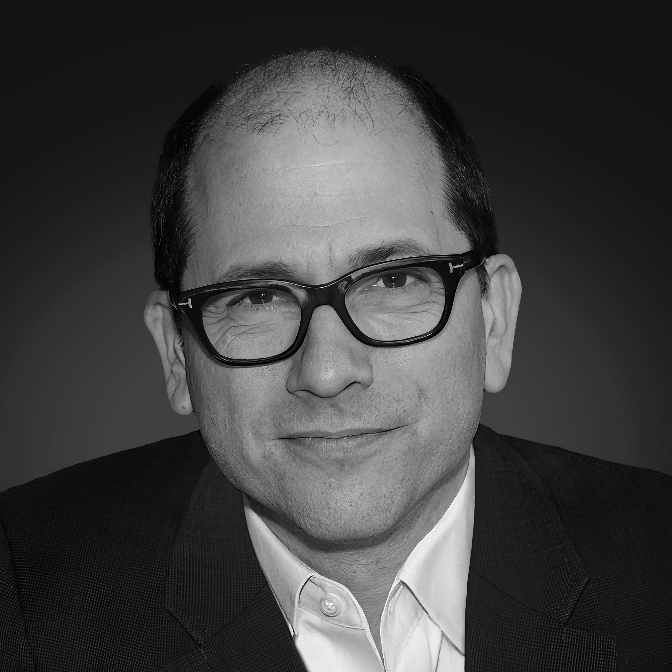 A smiling man with glasses wearing a suit