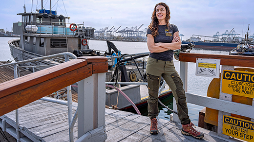 A woman standing next to a boat with her arms crossed
