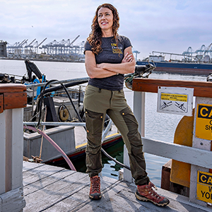 A woman standing next to a boat with her arms crossed