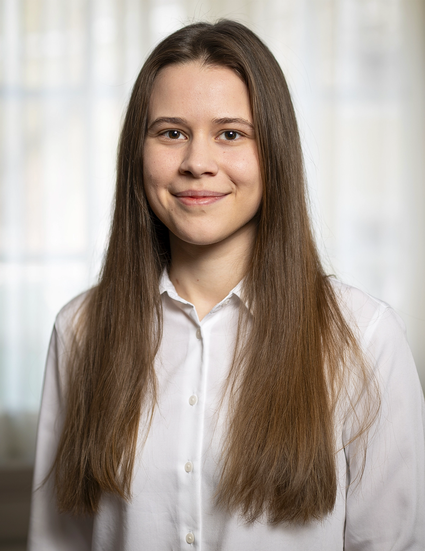 A smiling woman with long hair in a white shirt