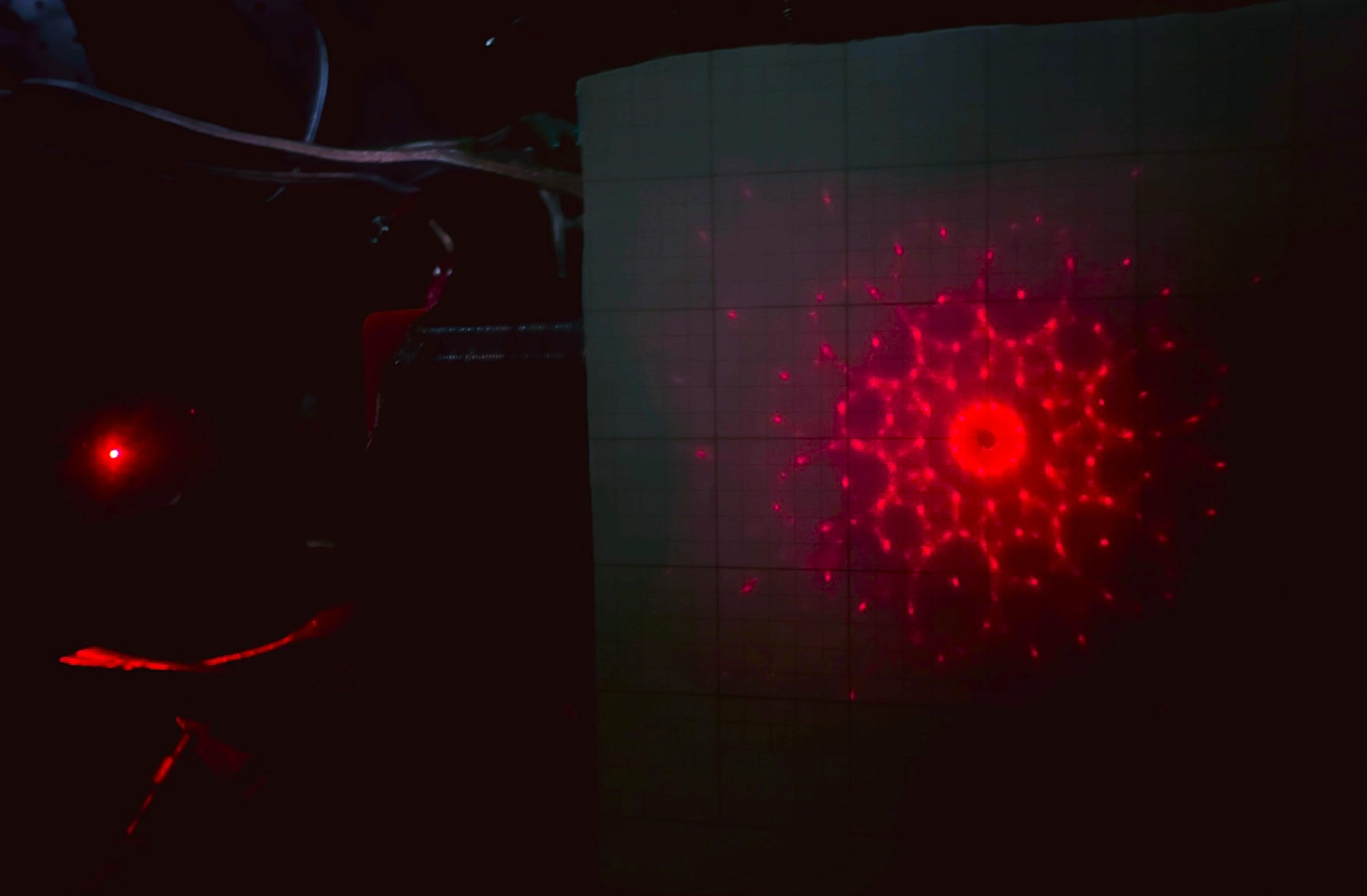 a photo of the bright red points of light of a diffraction pattern on a dark background.