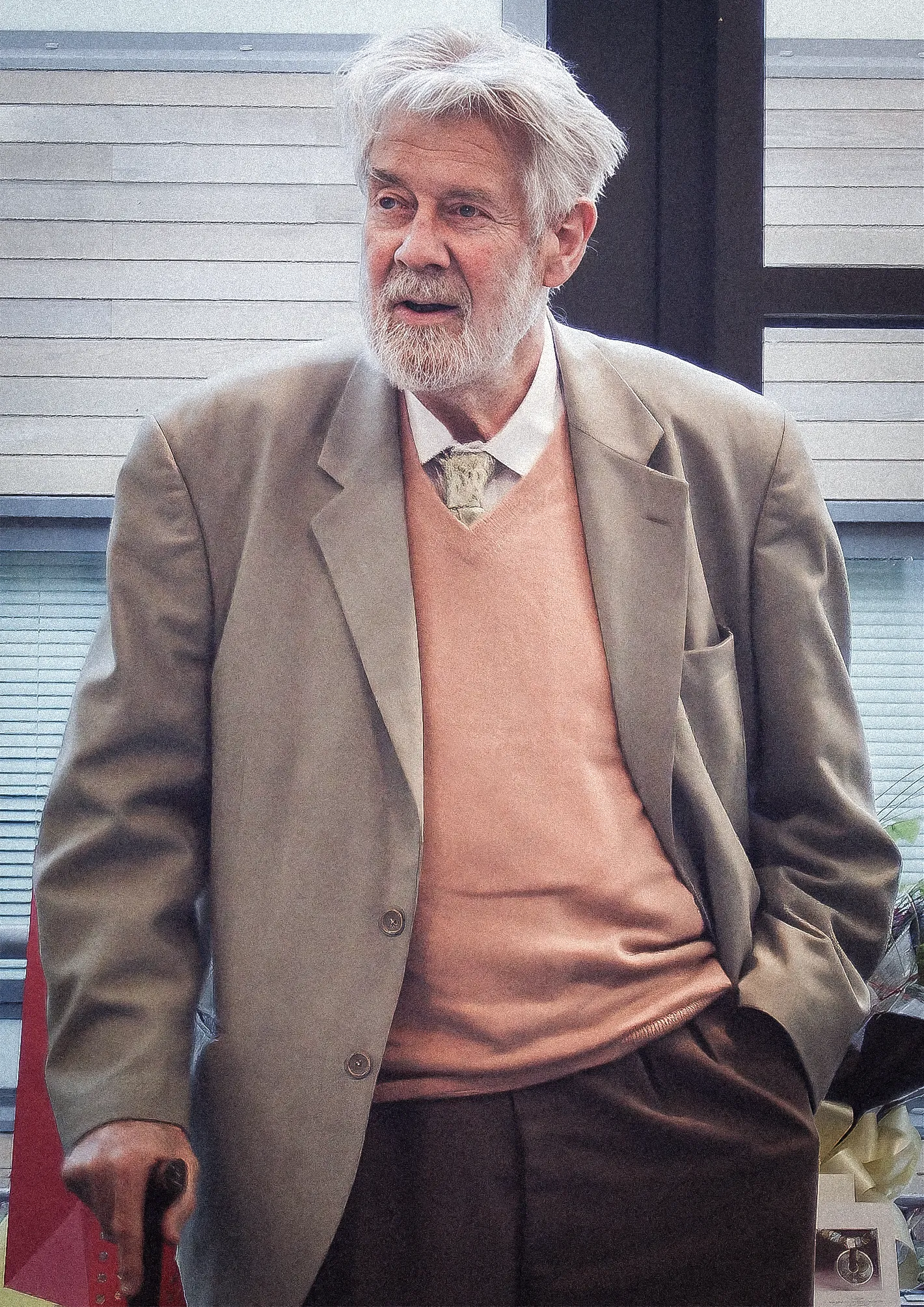 White-haired man leaning on a cane.