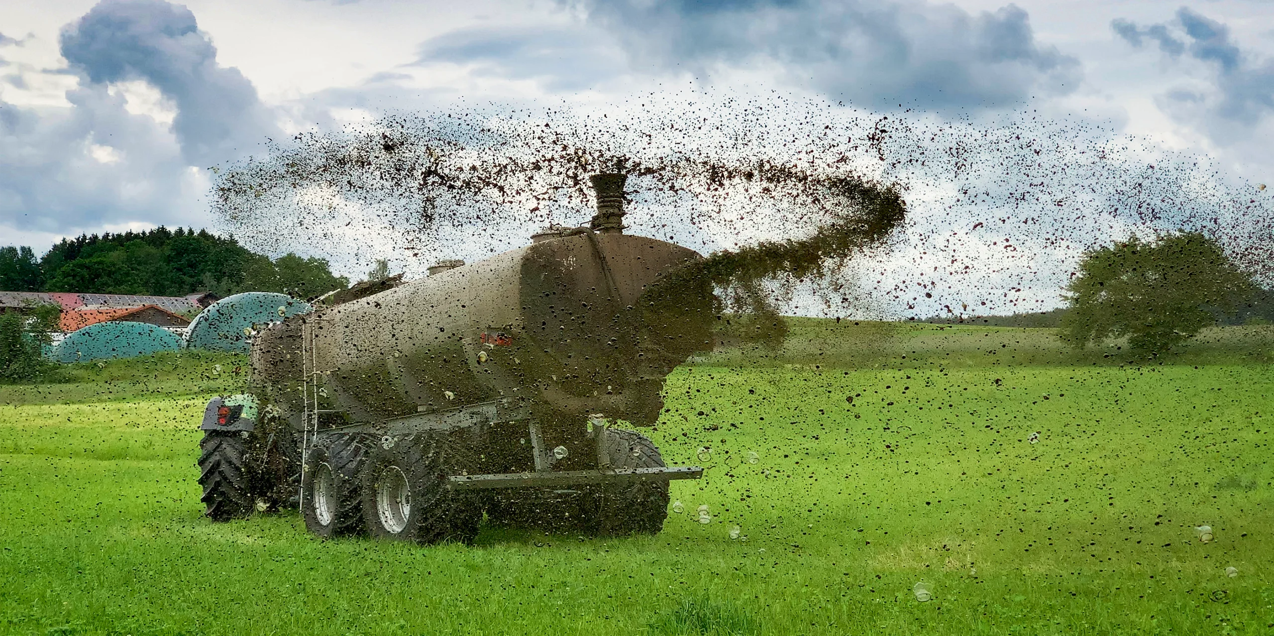 A tractor spews fertilizer onto a field