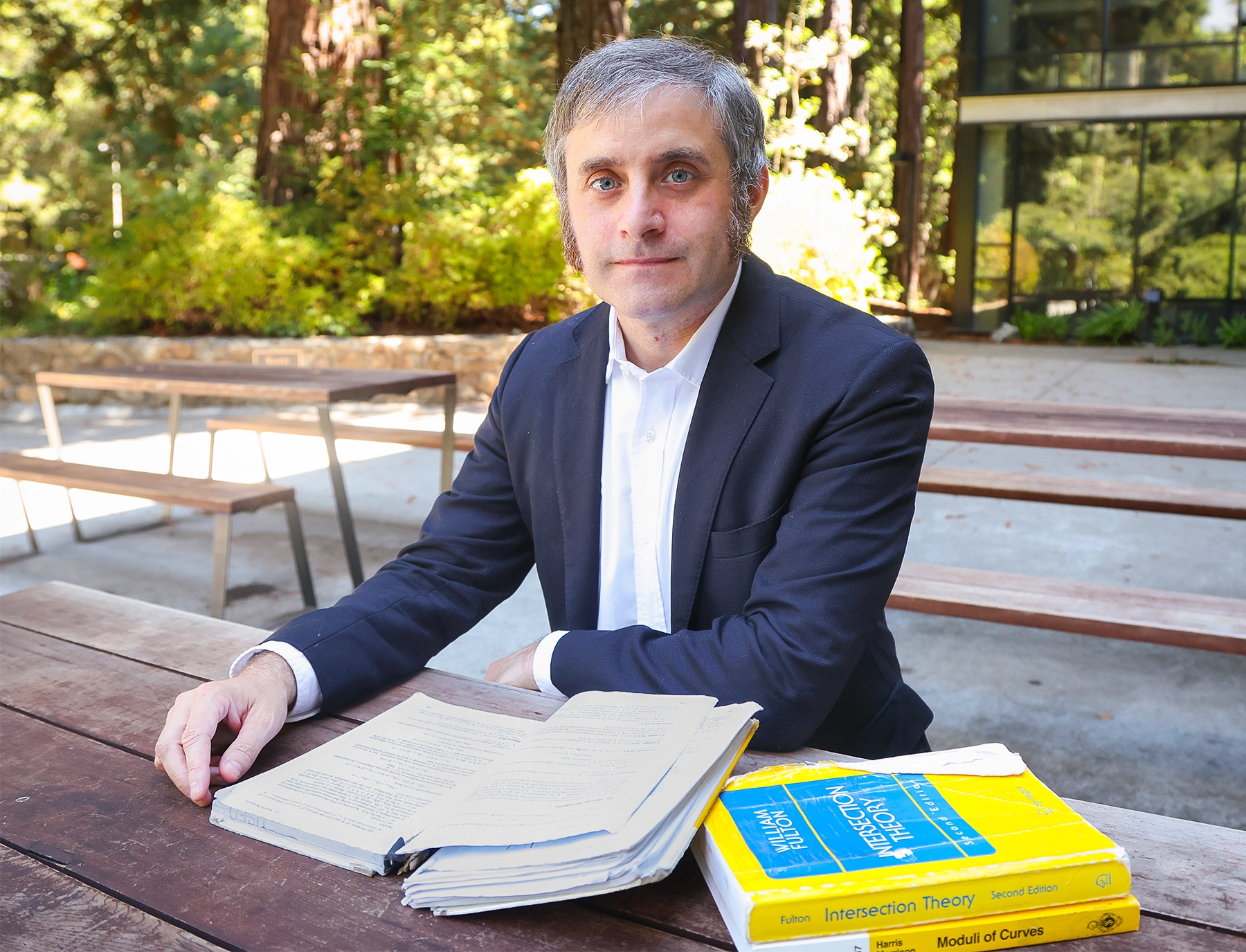 Man reading papers at an outdoor table.
