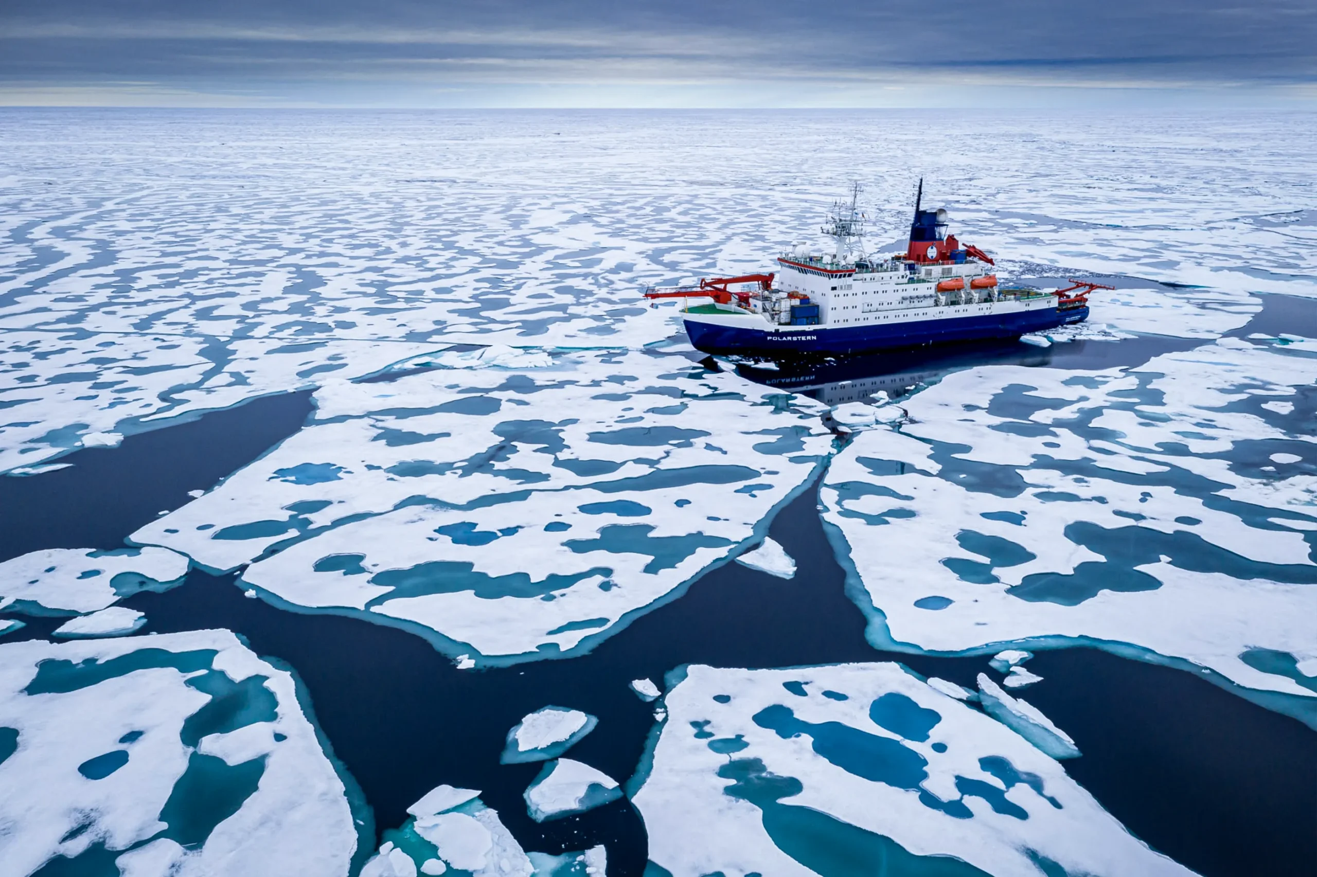 A ship navigating between cracked pieces of ice.