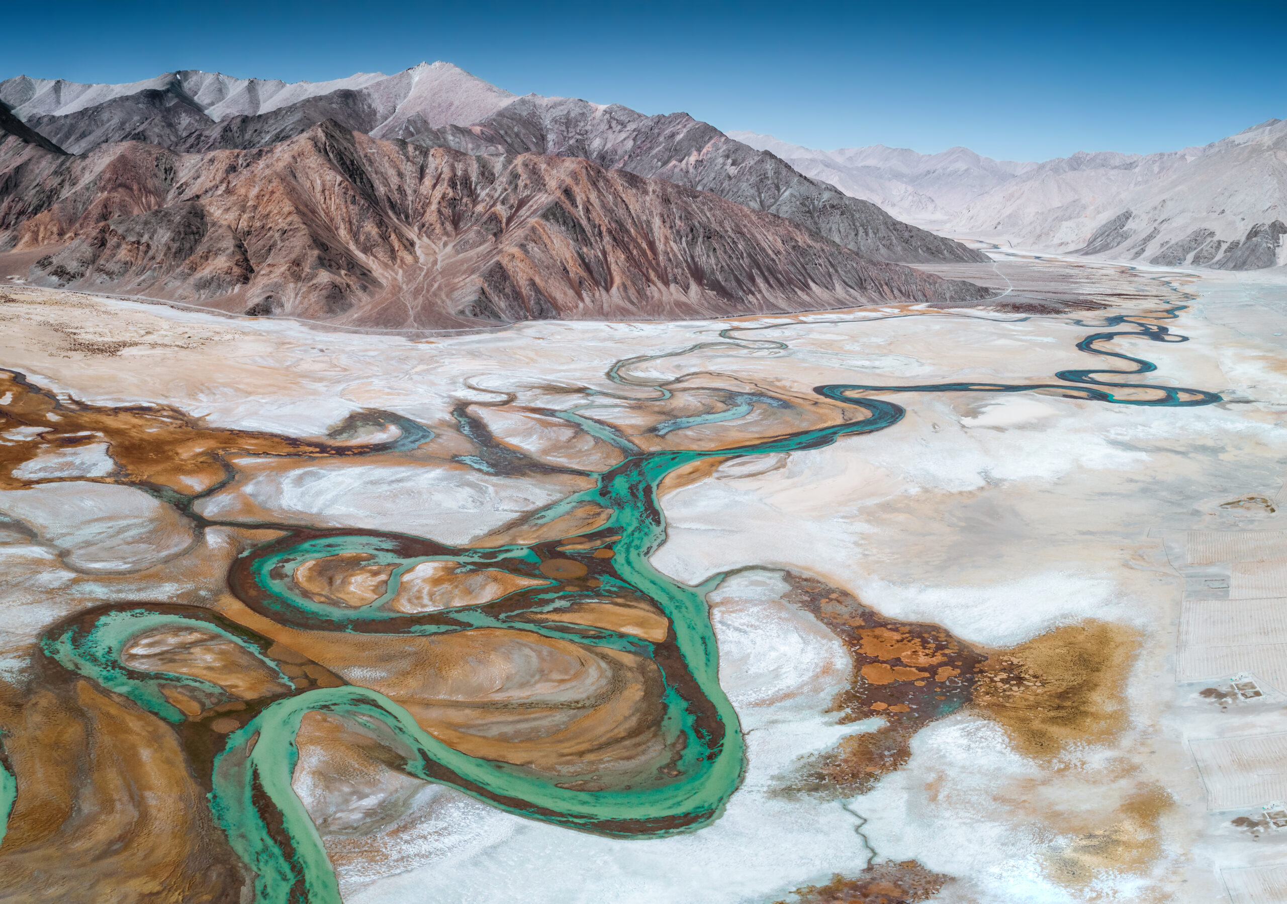 Aerial photo of a desert river at the base of mountains.