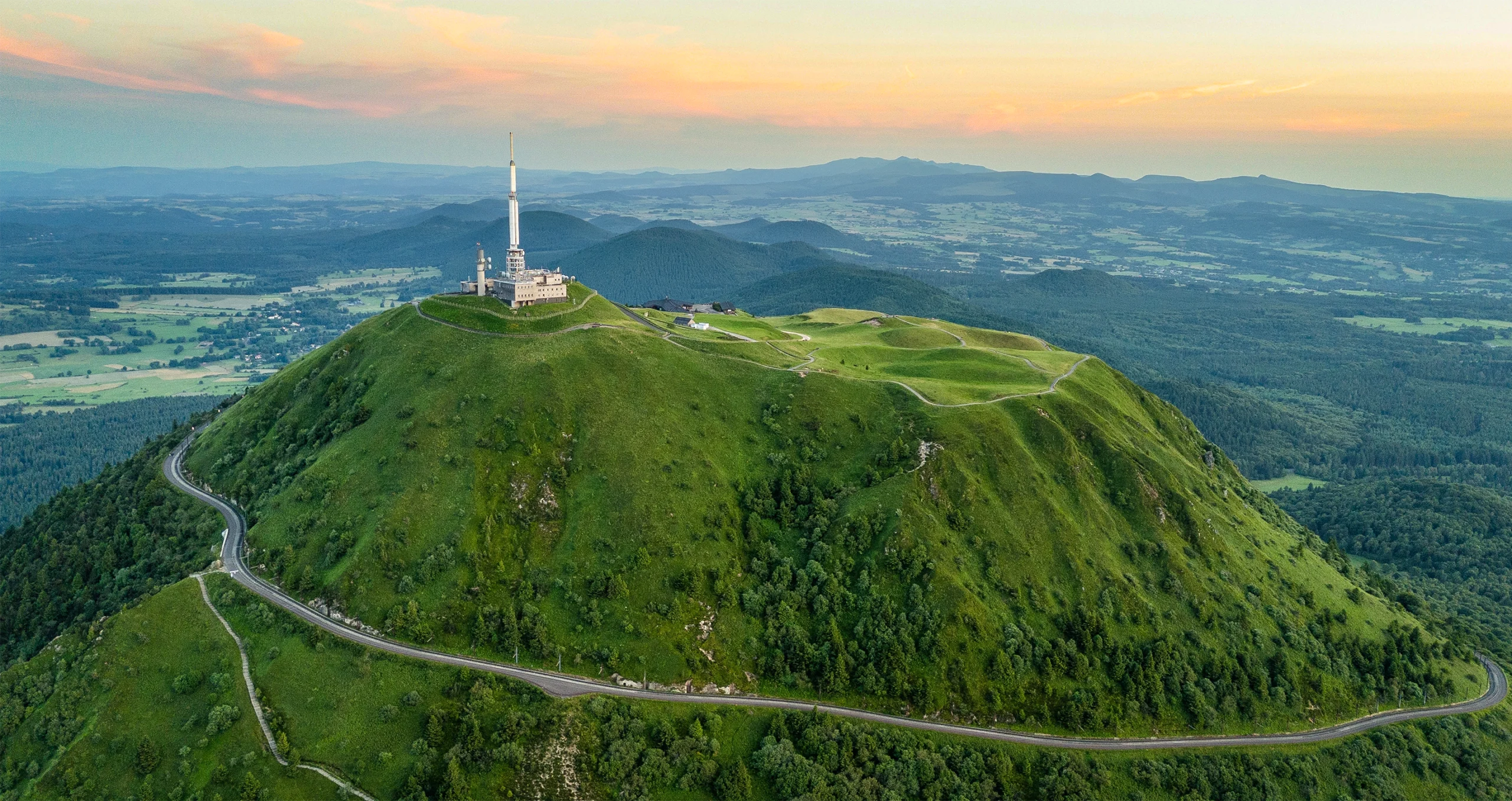 A tall white tower on top of a hill.