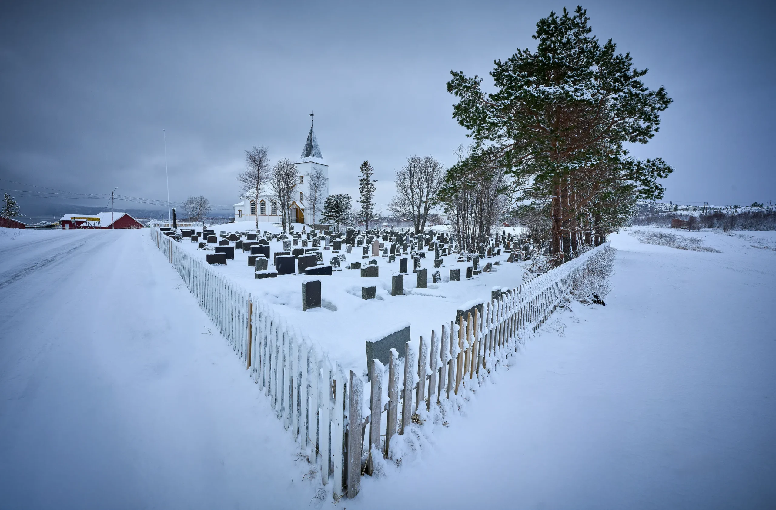 Snow-covered church and graveyard in Norway.