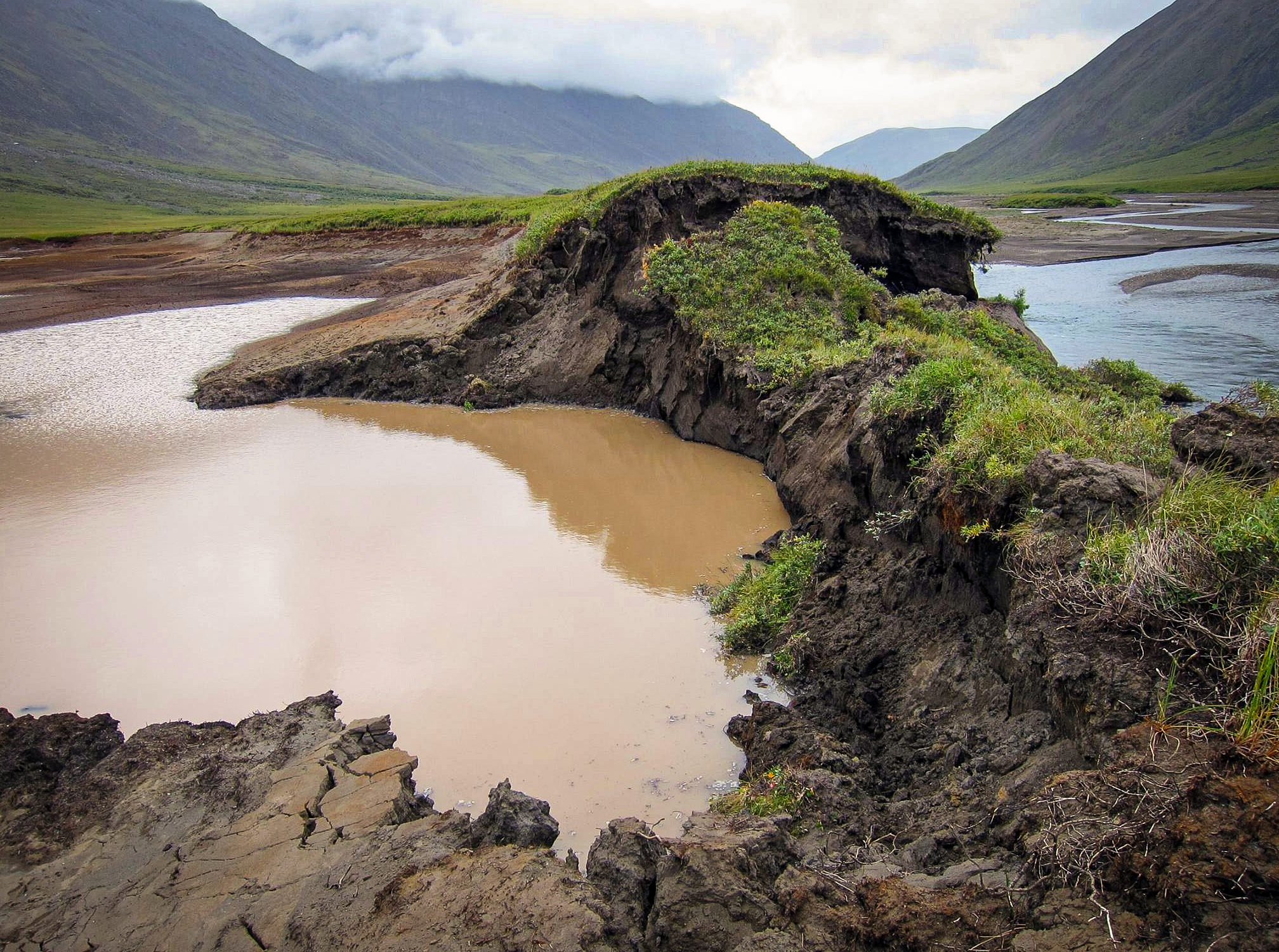 A mound of collapsed earth ringed by muddy water