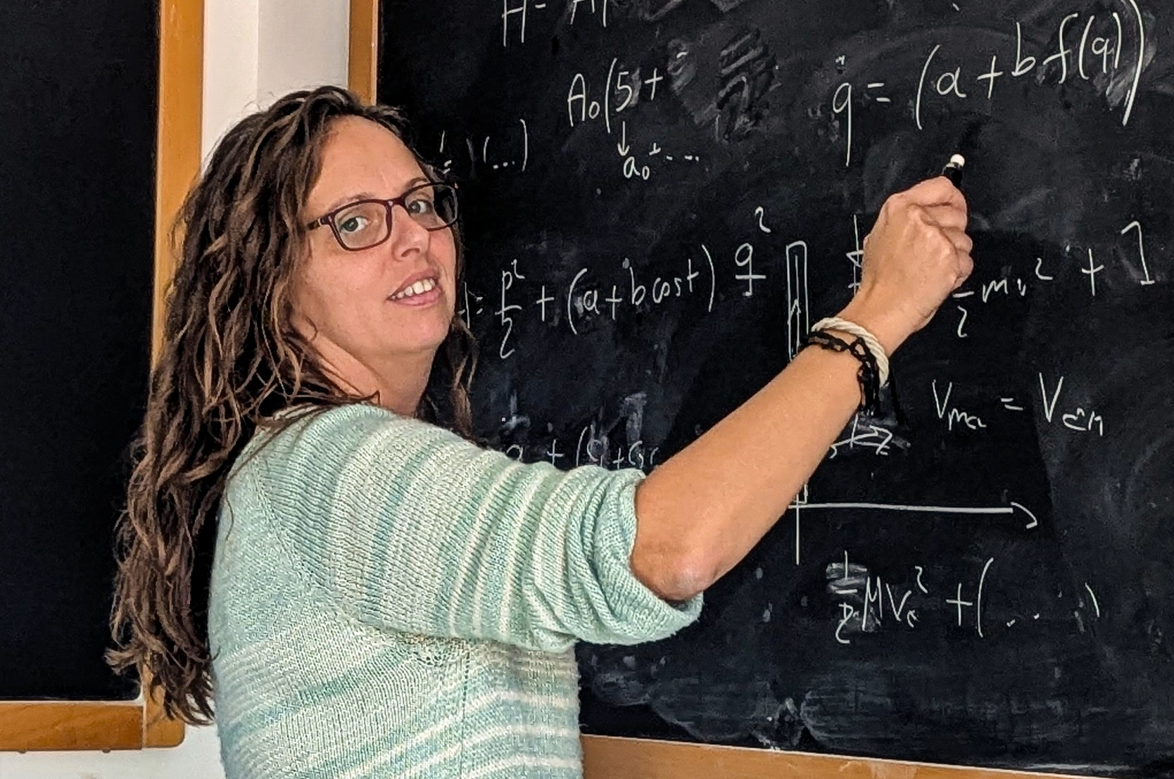 Woman writing at a blackboard.