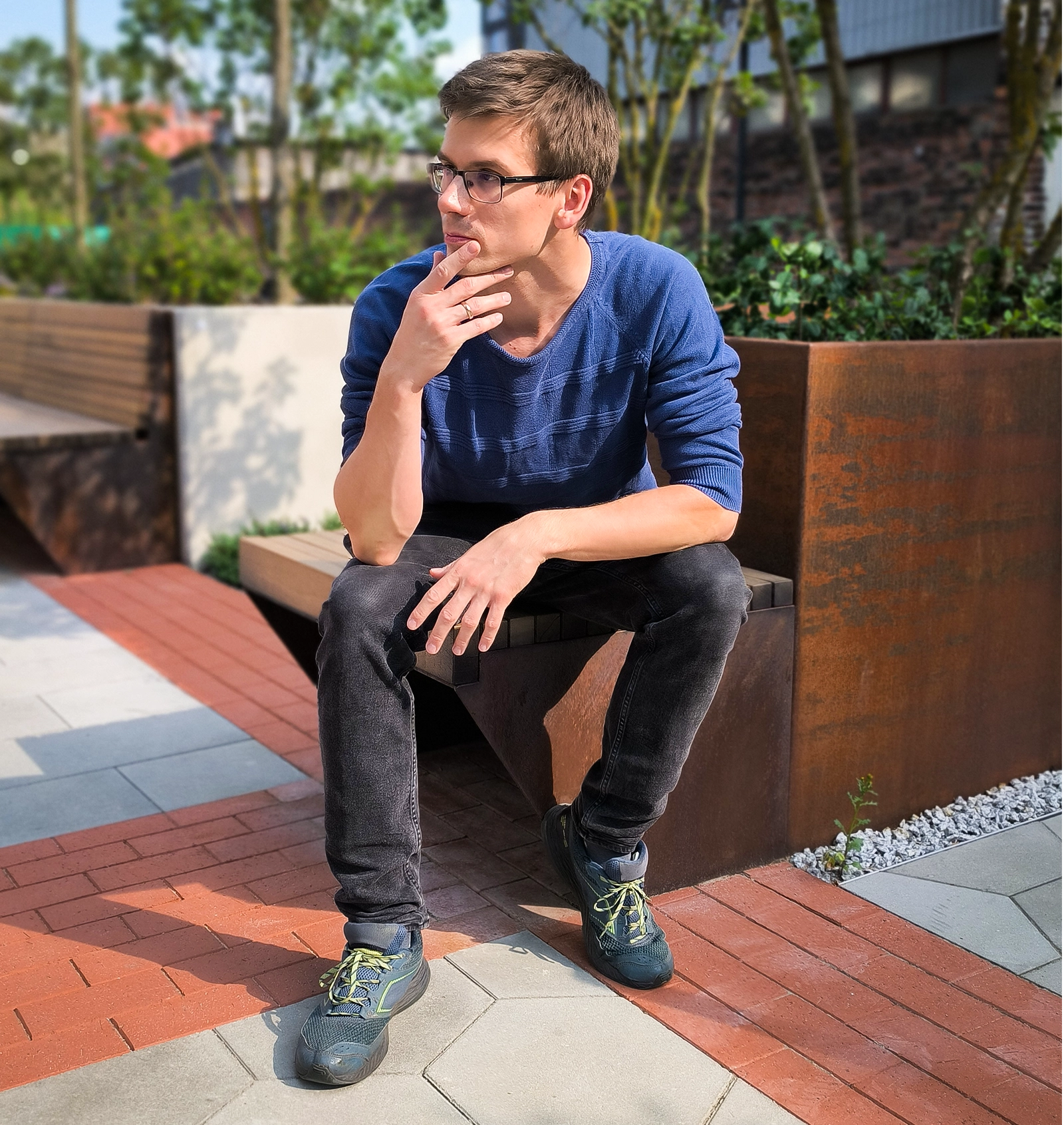A man sits outside on a bench.