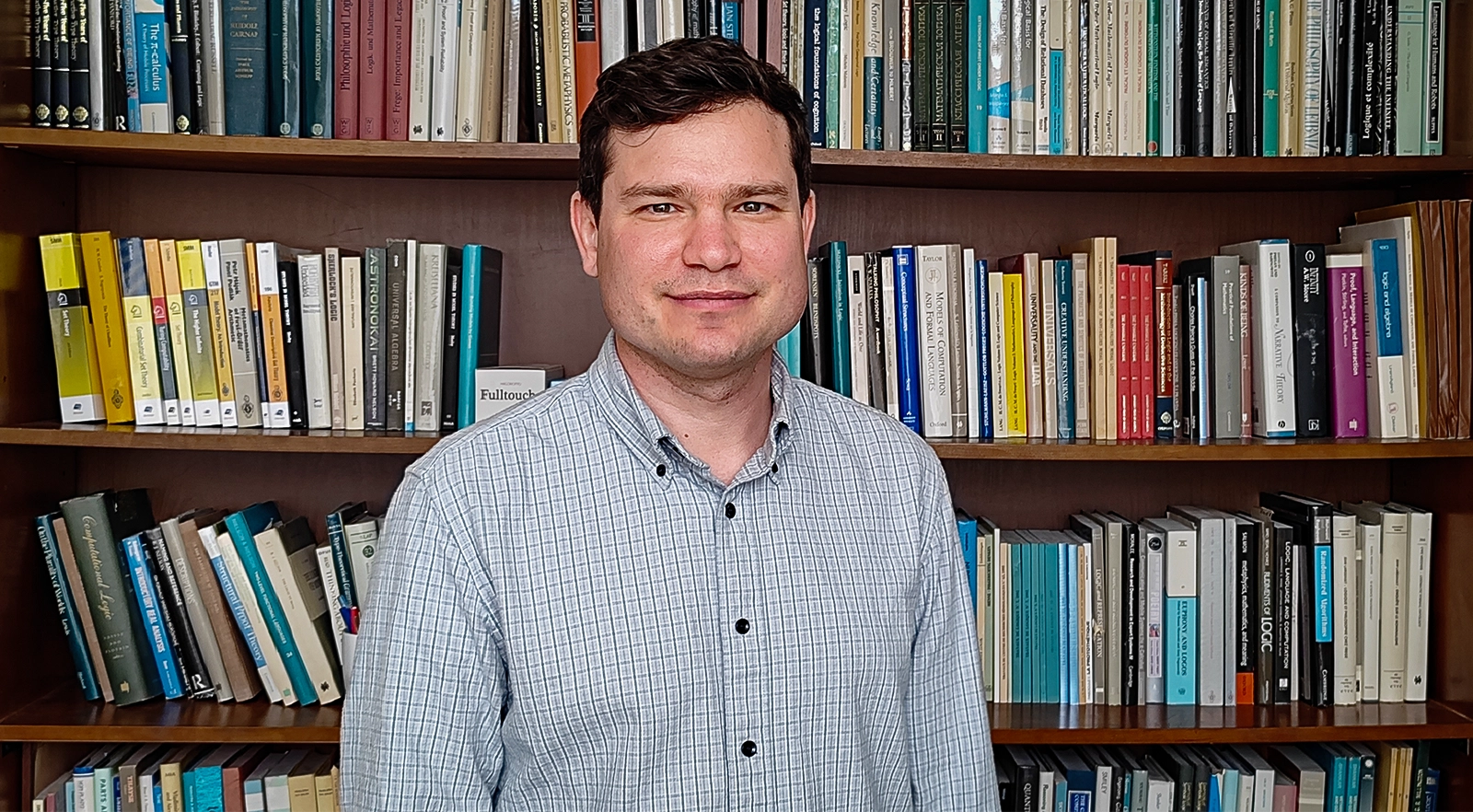 A man standing in front of a colorful bookshelf