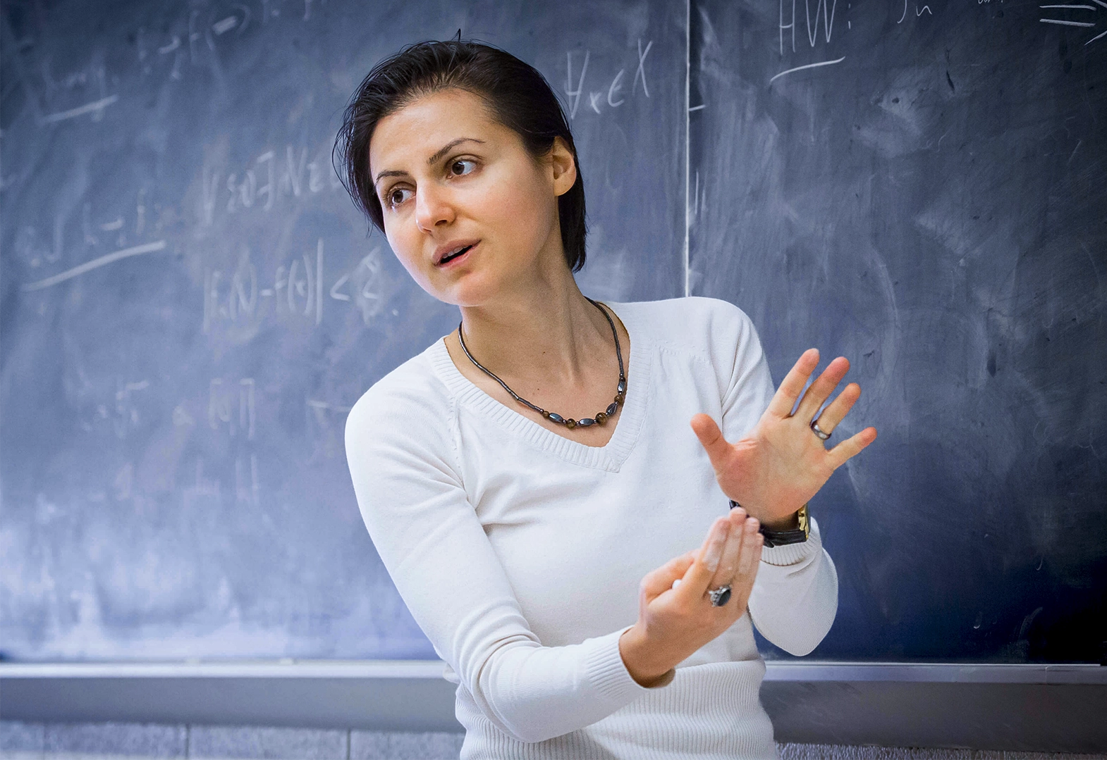 Short-haired woman in front of a blackboard.