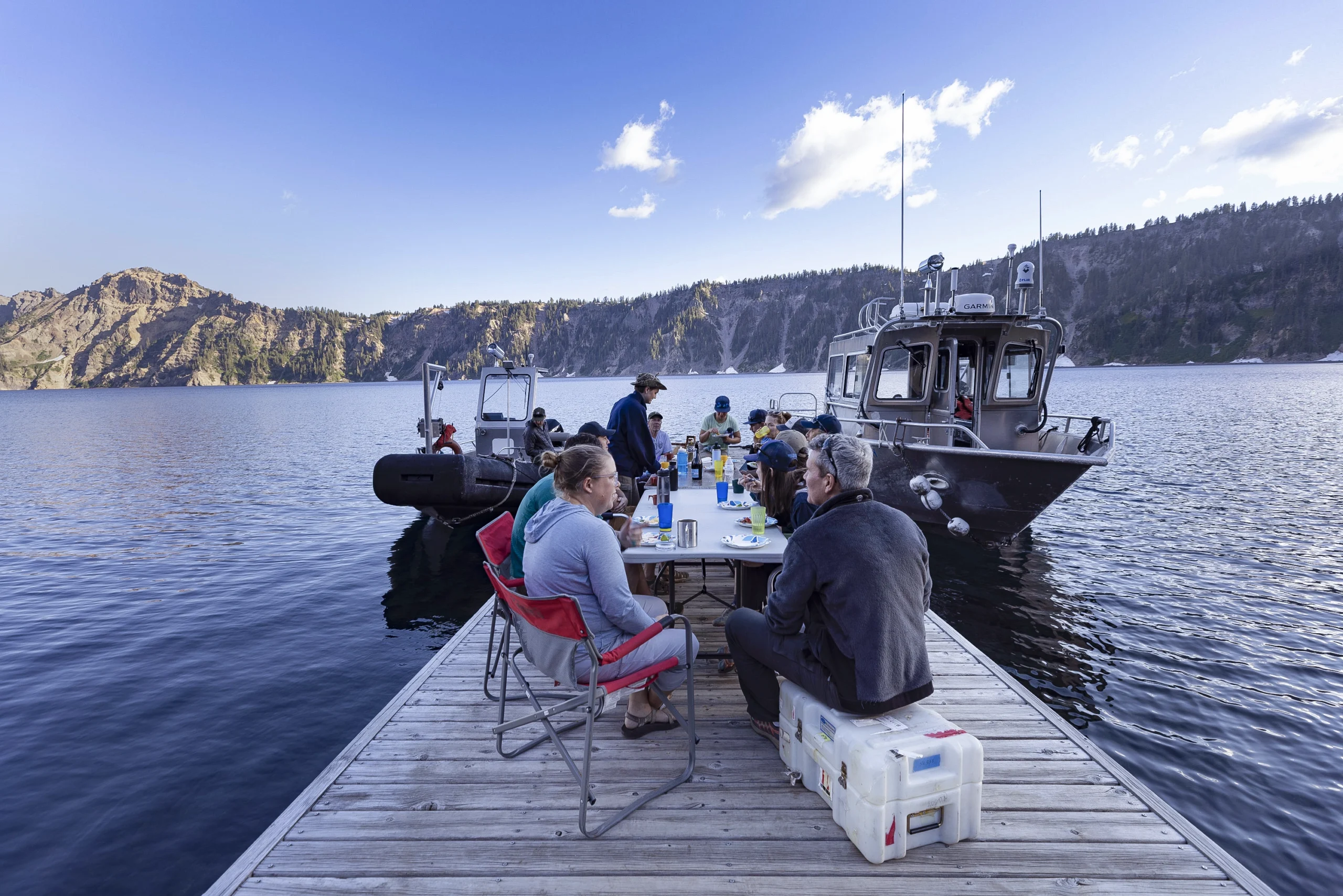Researchers sit around a folding table on the dock to share a meal.